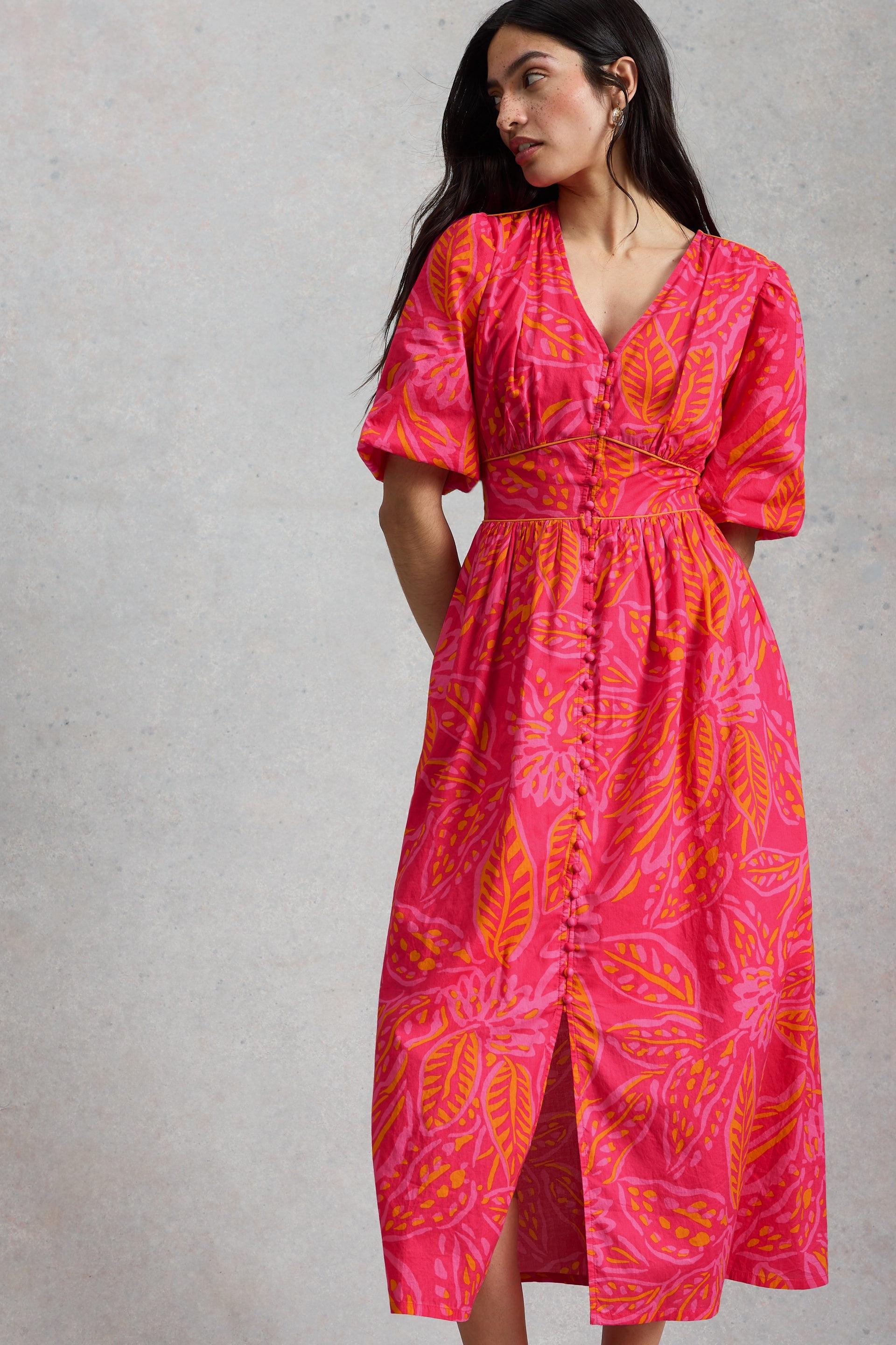 Woman wearing a pink and orange leaf-patterned organic cotton midi dress against a plain background.