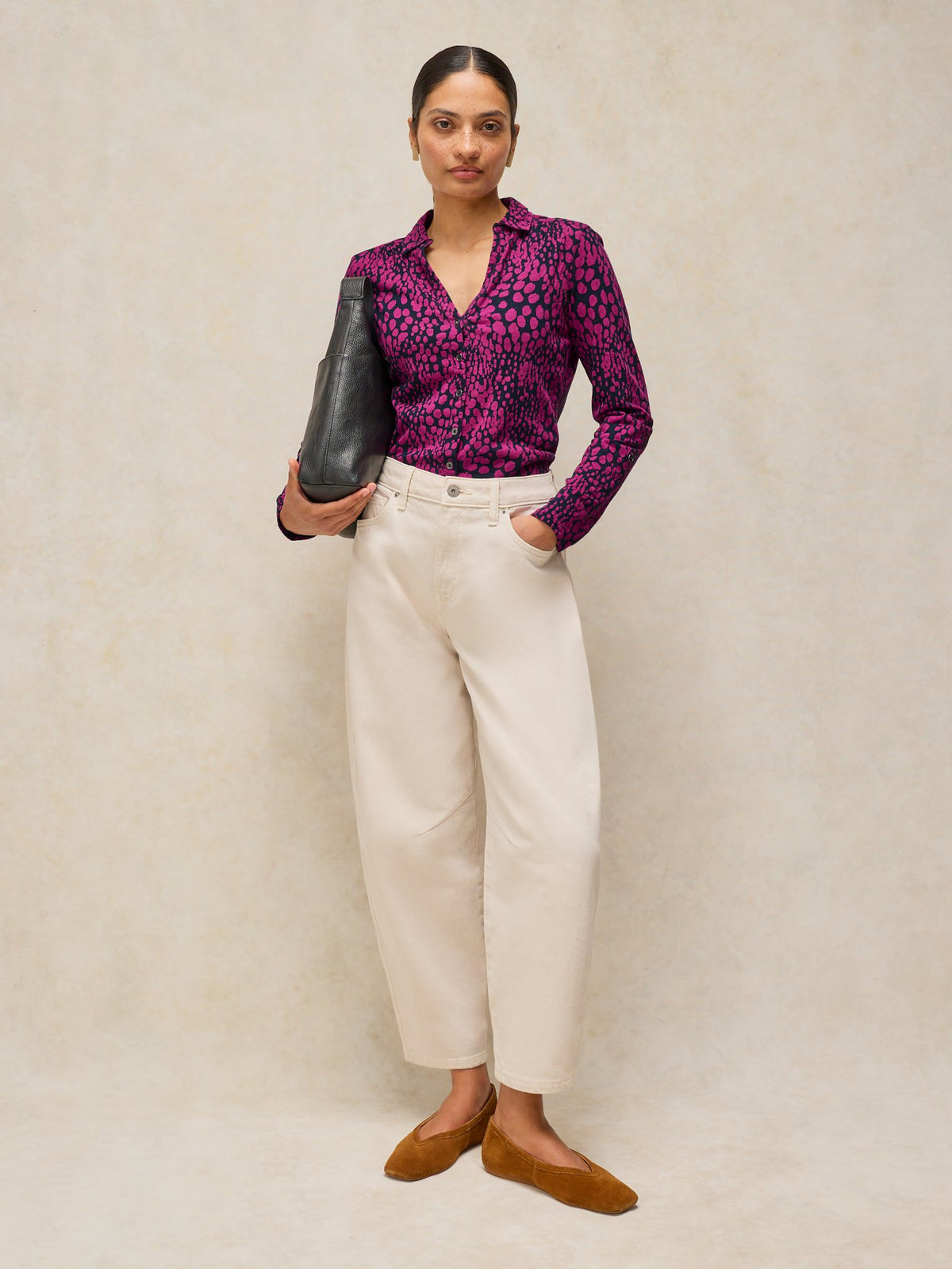 A woman modelling a pink leopard print button-down blouse paired with casual white jeans and brown flats.