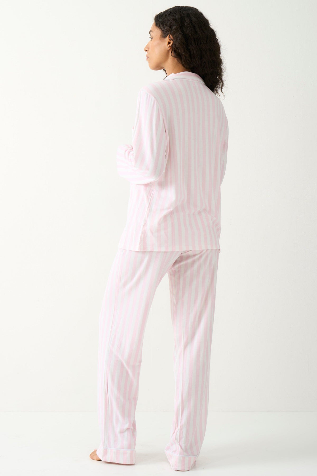 A woman standing back to camera wearing pink stripe tencel pyjamas from Stripe & Stare