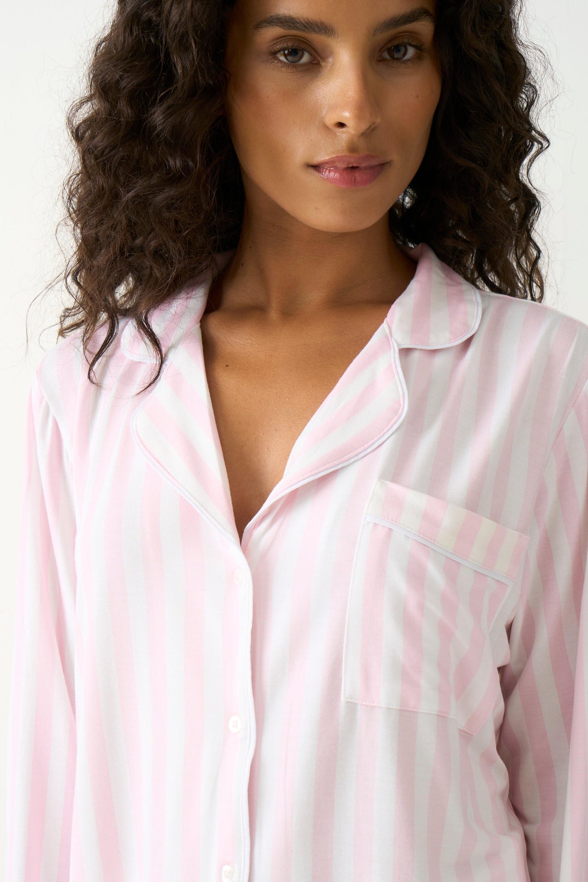 Woman with curly hair wearing soft pink stripe tencel pyjamas