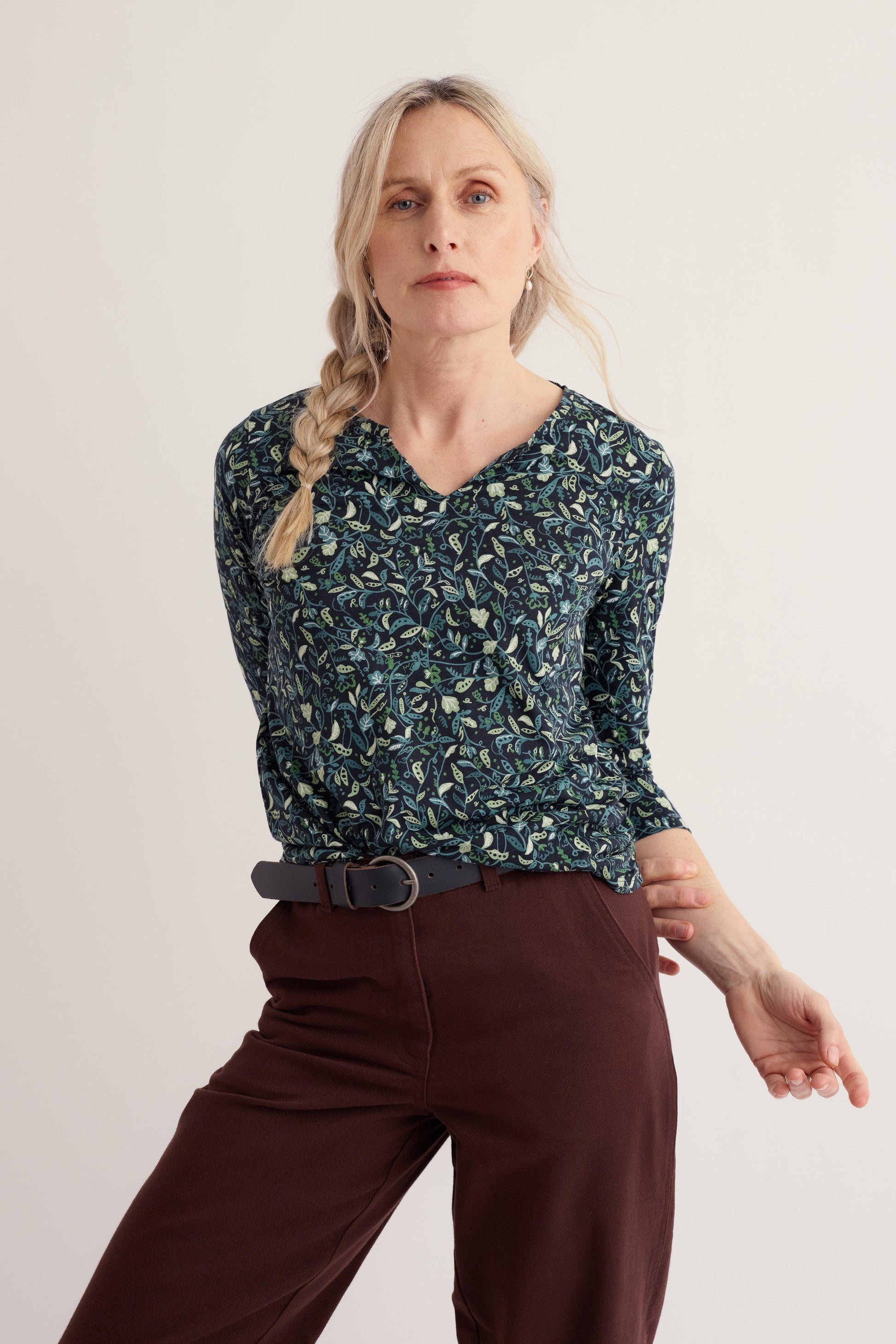 A woman wearing a long-sleeve organic cotton top with a green leaf print against a neutral background.