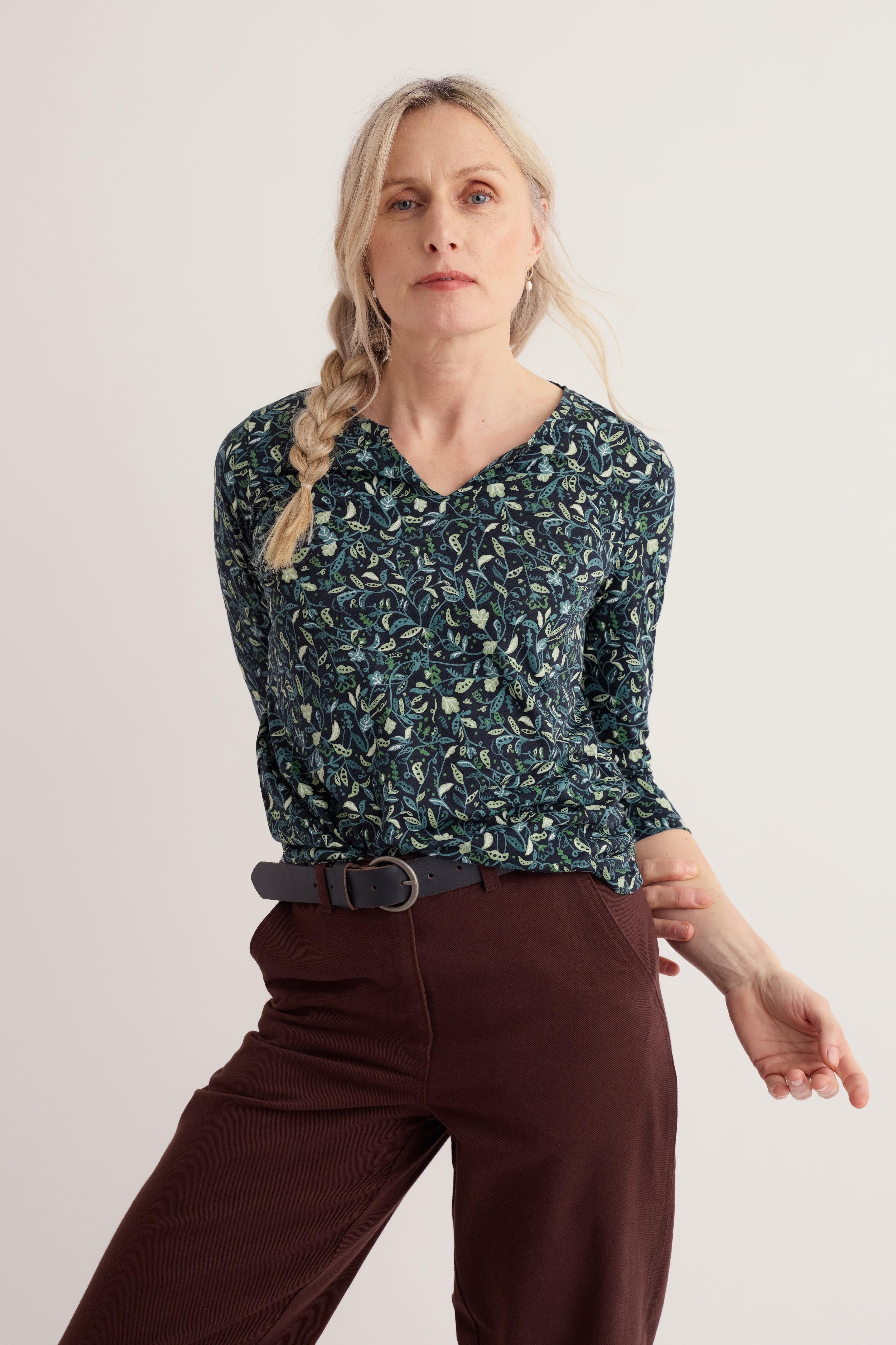A woman wearing a long-sleeve organic cotton top with a green leaf print against a neutral background.