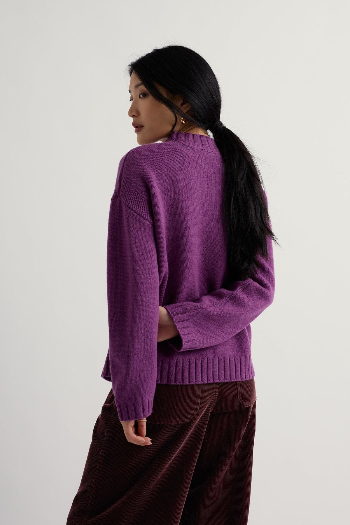 A woman posing in a vibrant purple knit jumper, perfect for autumn and winter outfits.