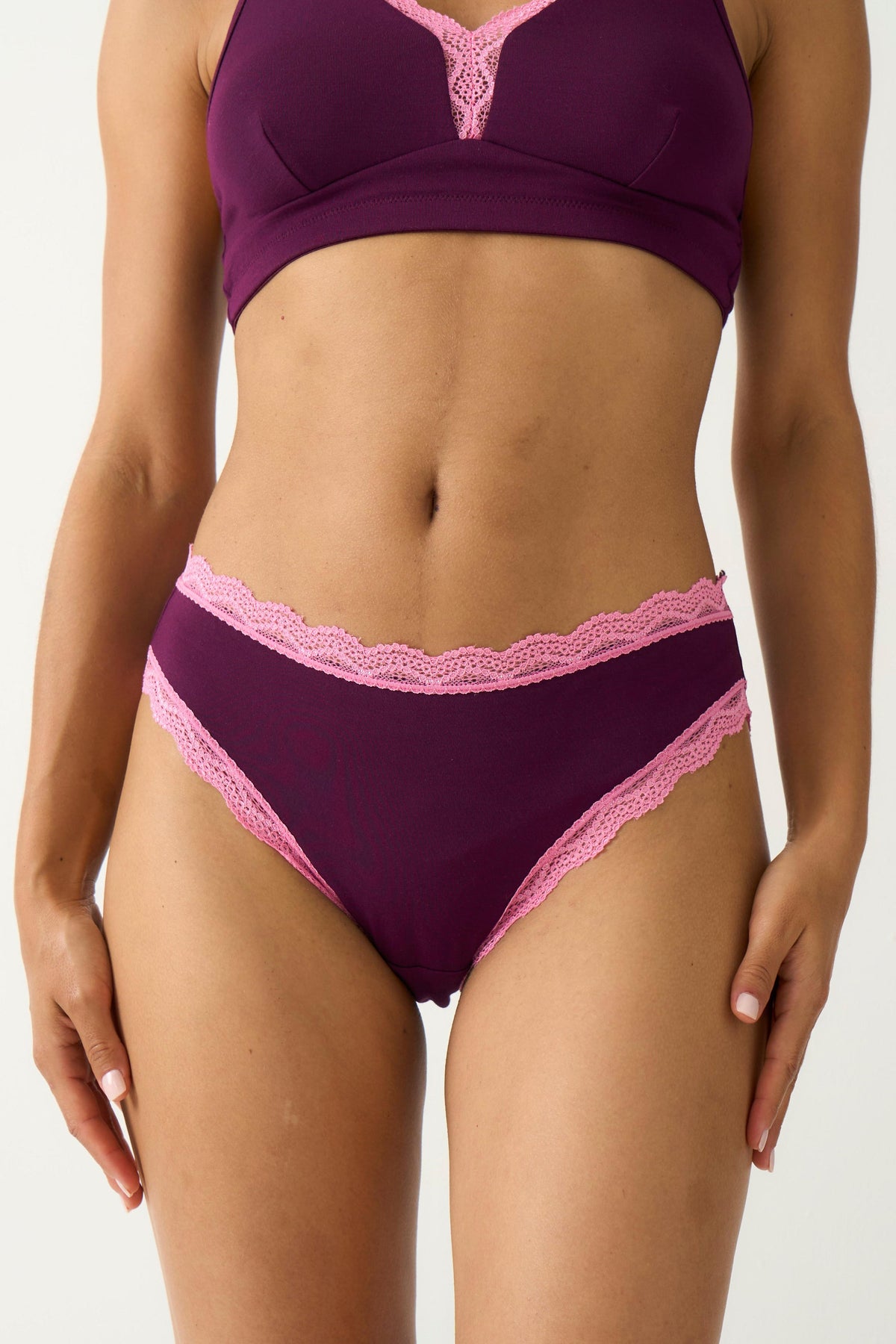 A woman wearing deep purple classic cut underwear with delicate pink lace trim.