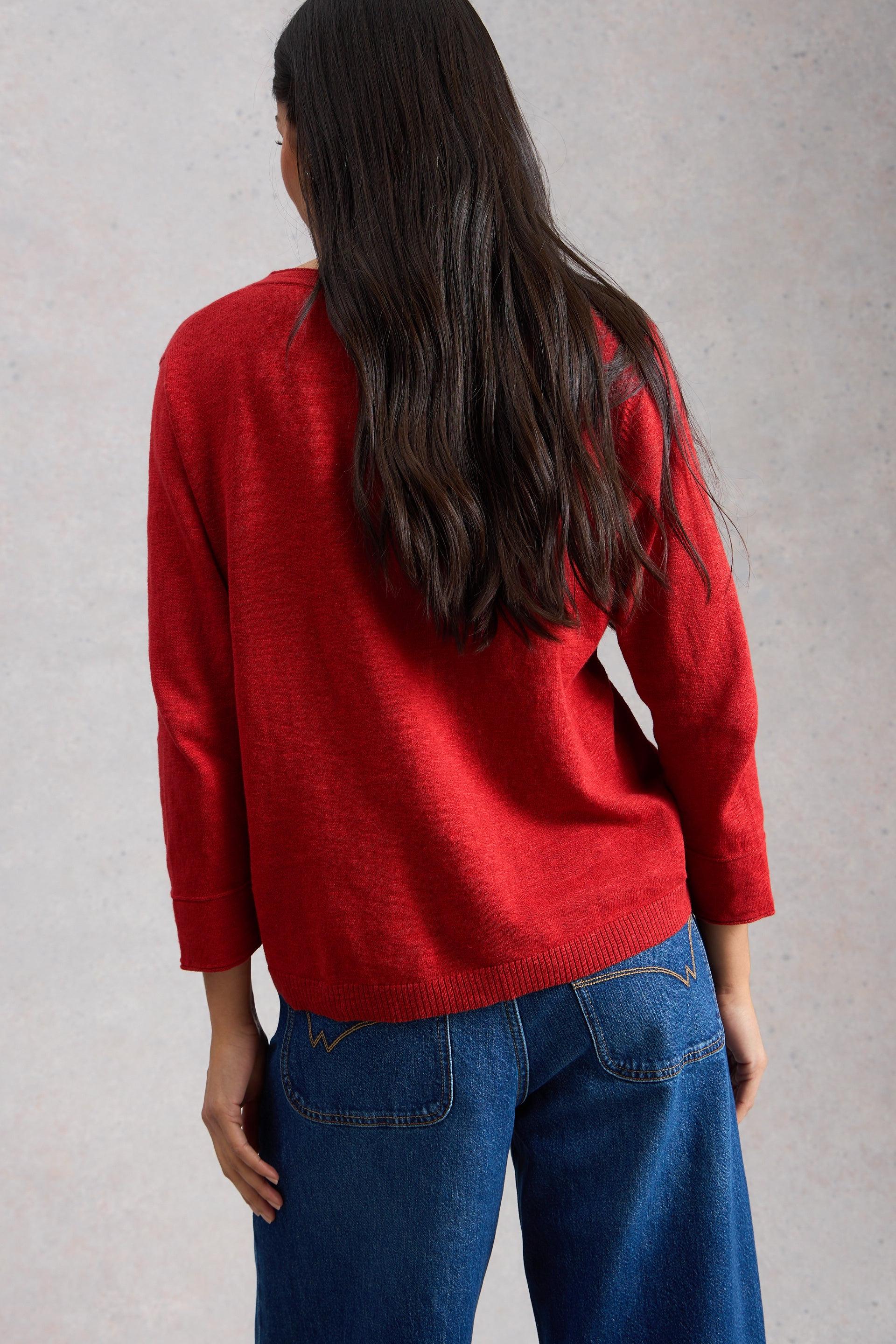 Woman seen from behind wearing a red v-neck sweater made of organic cotton.
