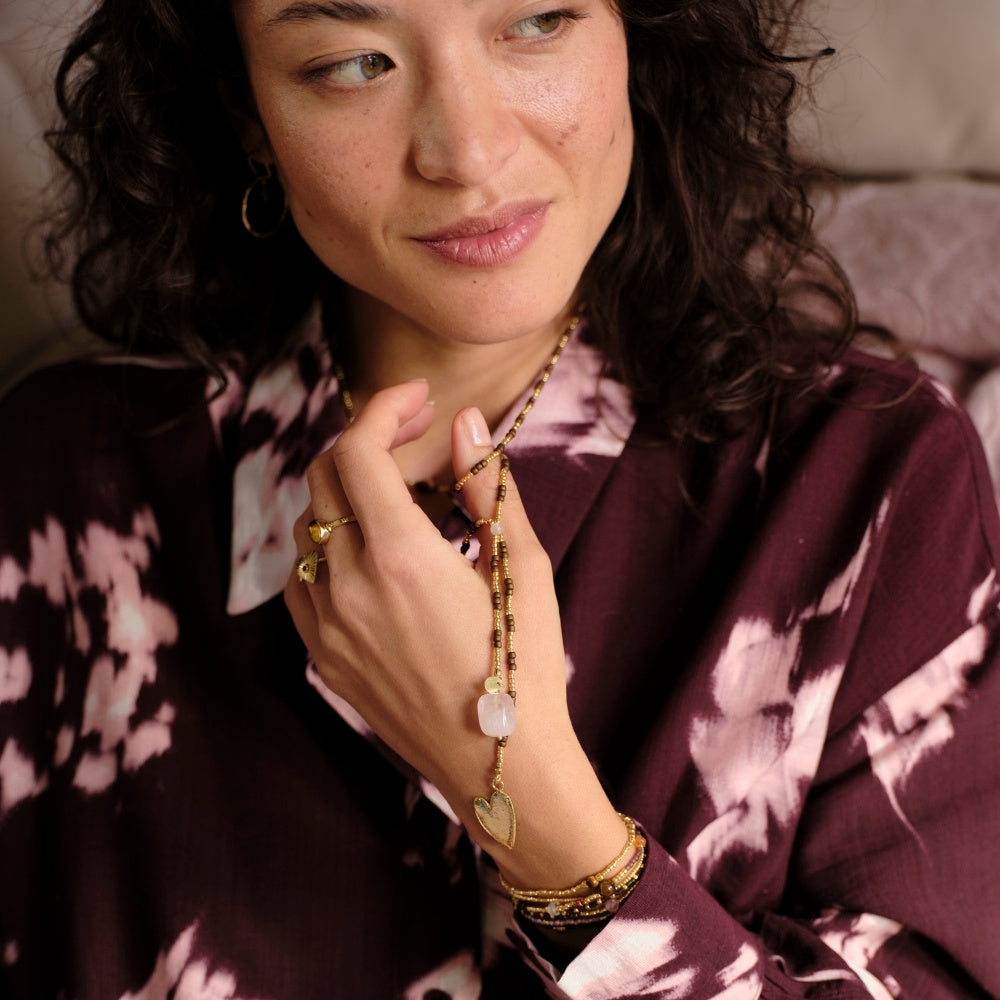 A woman wearing a delicate rose quartz gemstone necklace, a perfect sustainable jewellery gift for her.