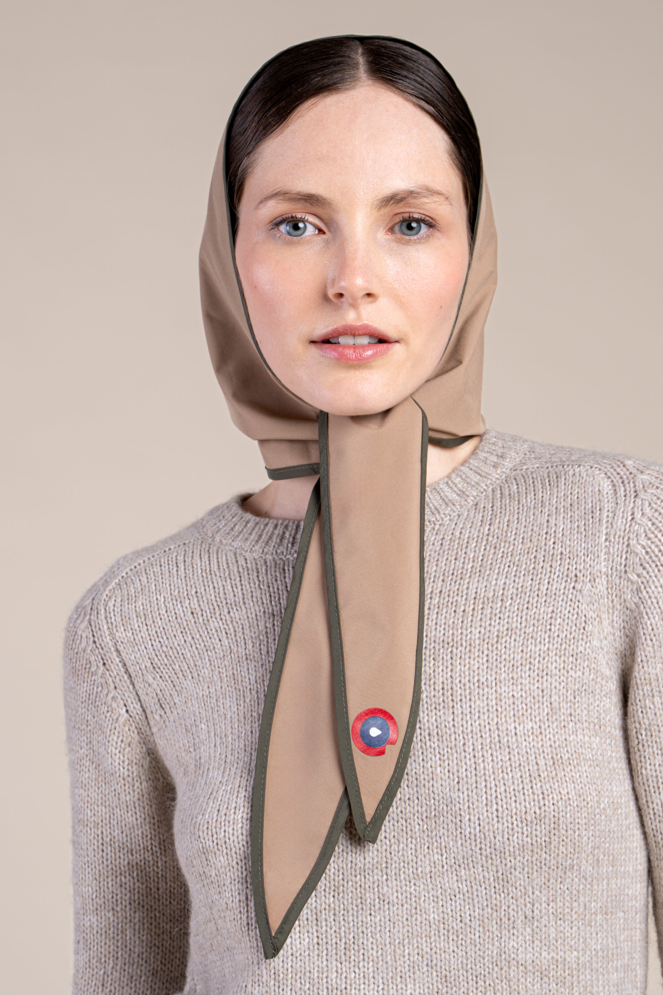 A woman wearing a modern, sahara colour waterproof head covering tied under the chin.