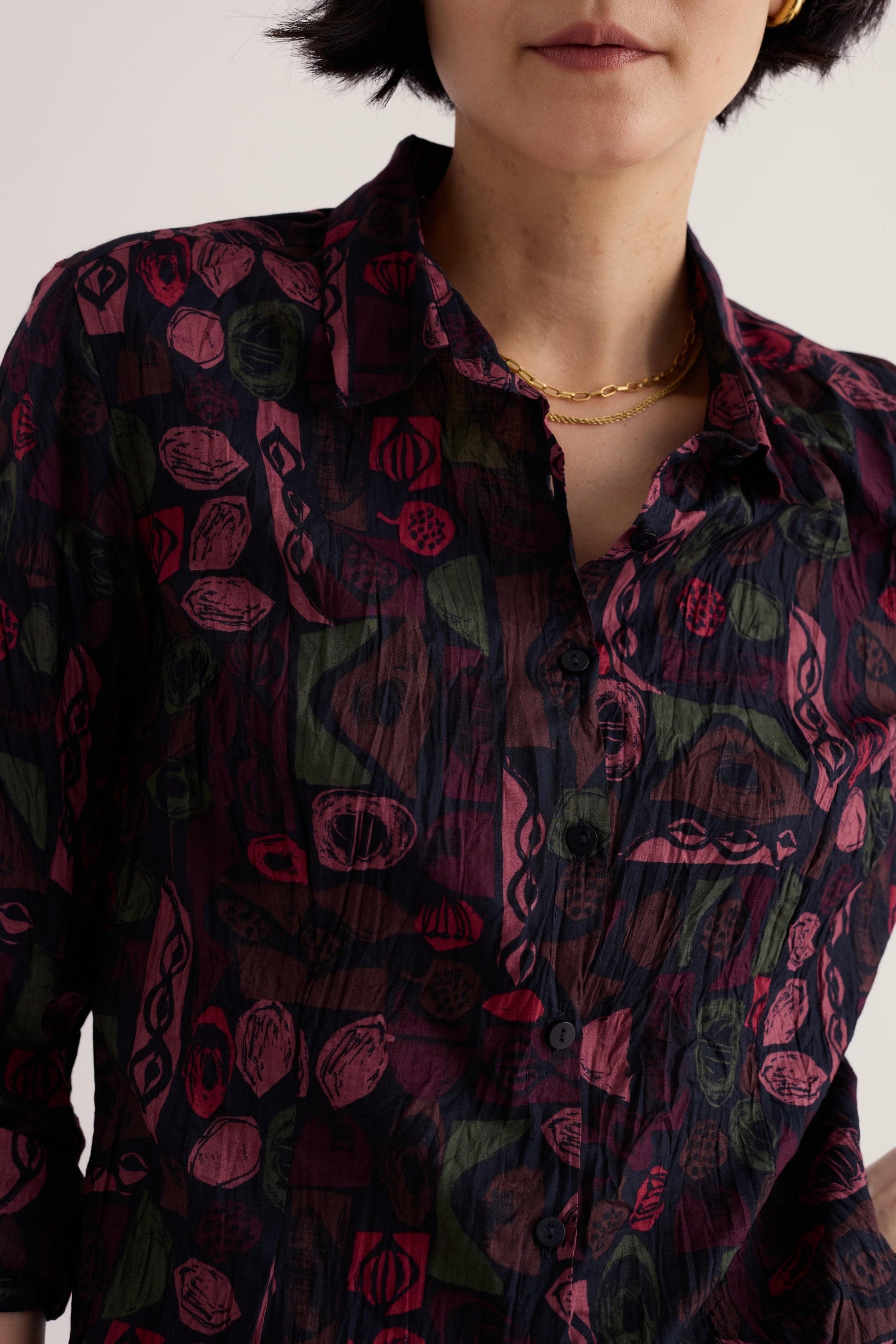 A woman wearing a dark patterned Seasalt Cornwall organic cotton button-down shirt against a neutral background.