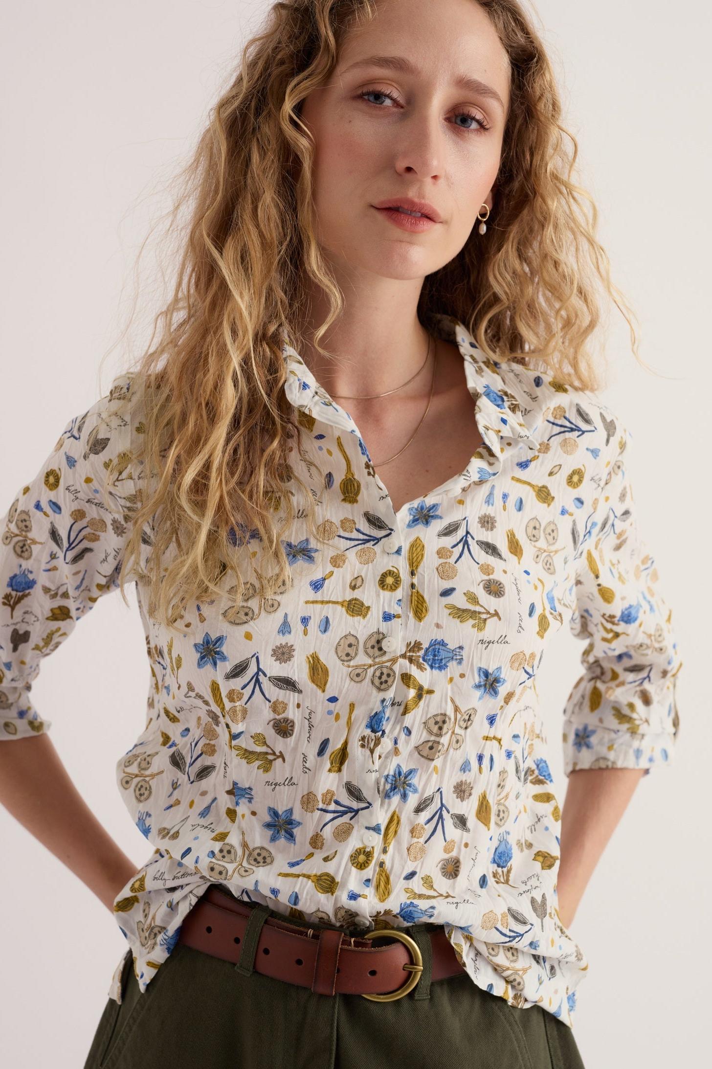 Woman wearing a Seasalt Cornwall white cotton shirt with a blue and olive floral botanical print.