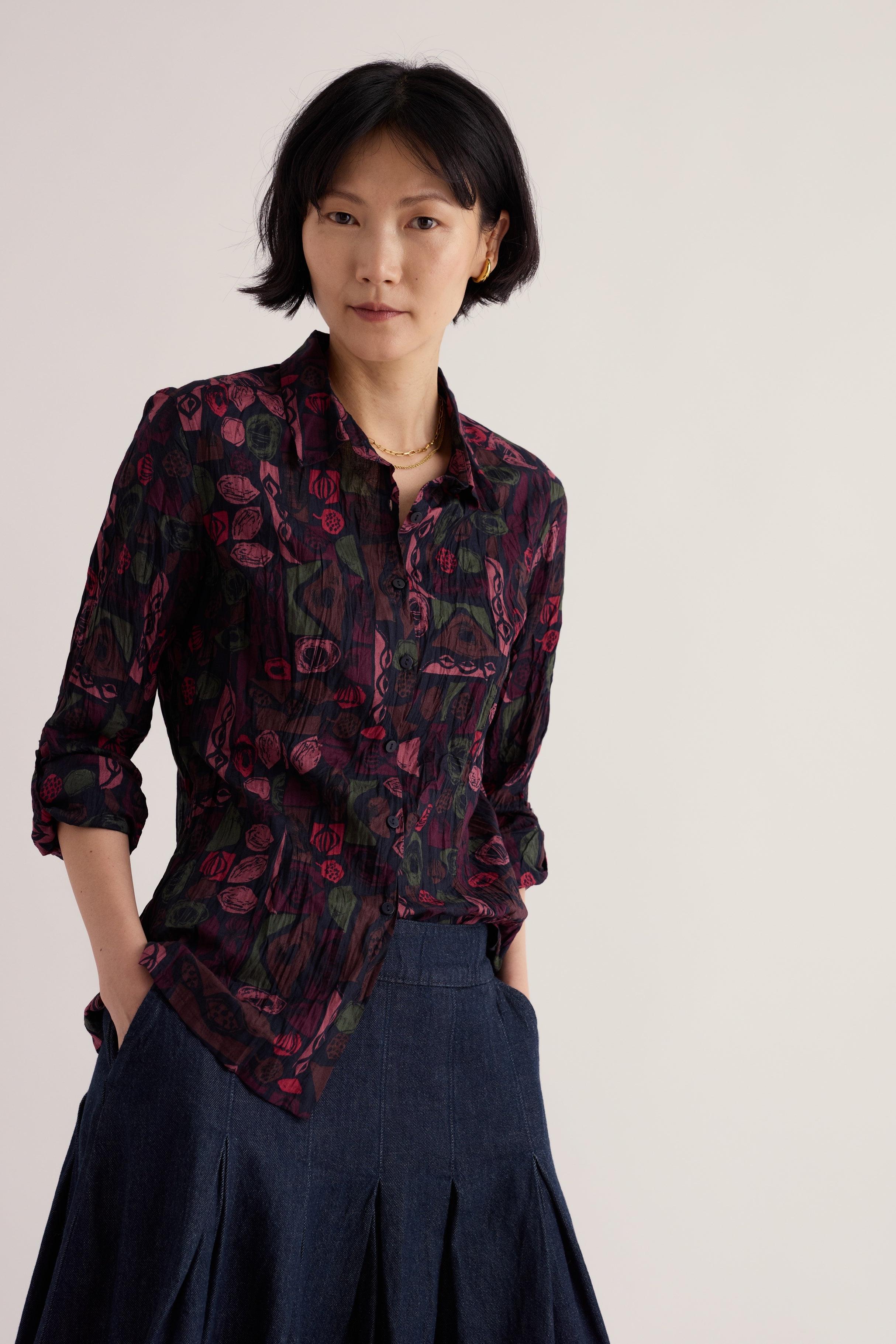 A woman posing in a Seasalt Cornwall Larissa organic cotton shirt with a dark abstract floral print.