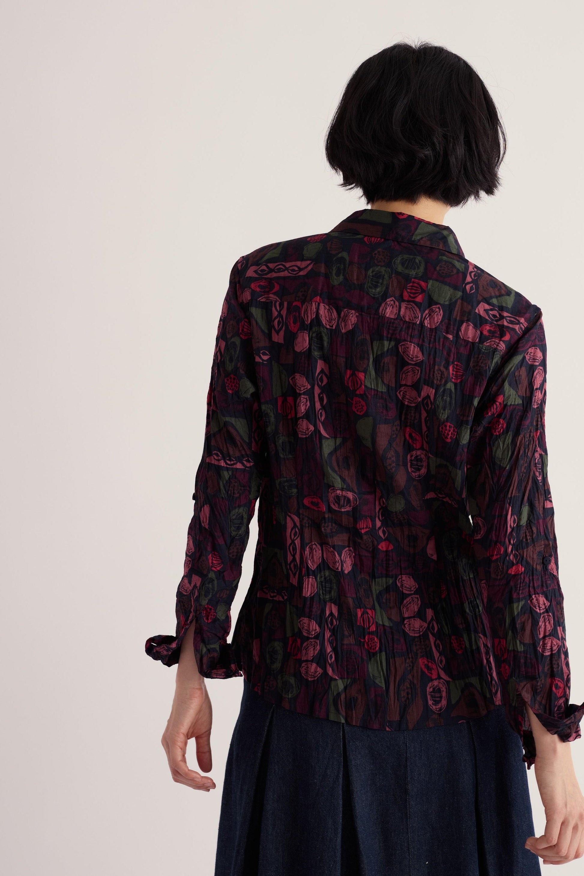 Back view of a woman wearing a patterned Seasalt Cornwall Larissa organic cotton shirt against a plain background.