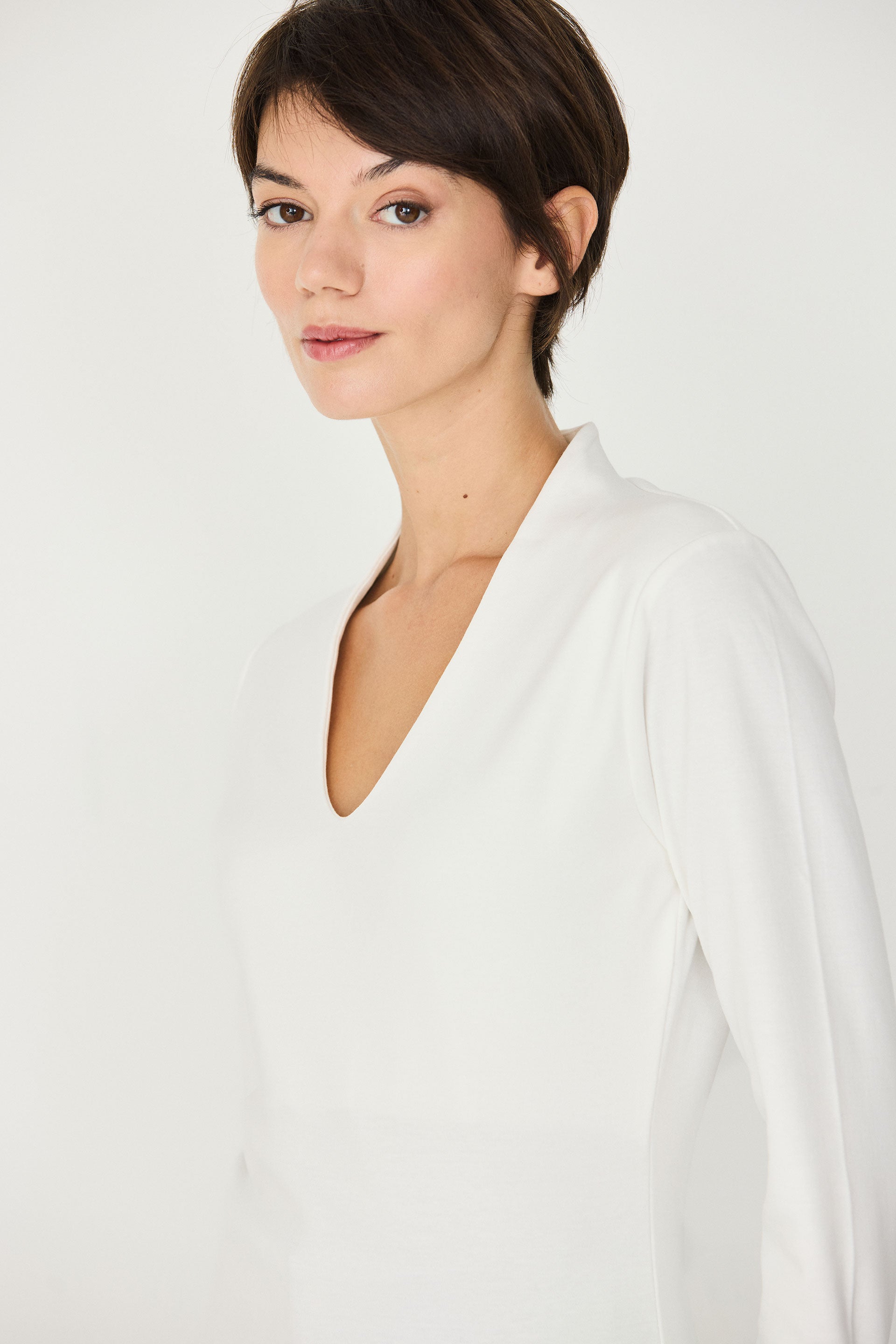 Woman with short hair wearing a sustainable SKFK organic cotton white long-sleeve top.