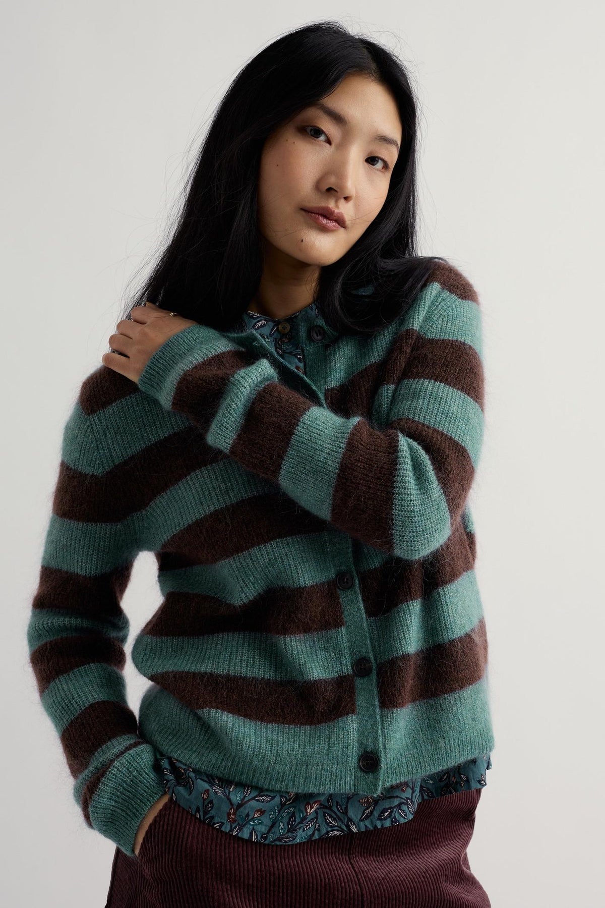 A woman posing in a blue and brown striped mohair knit cardigan by Seasalt Cornwall.
