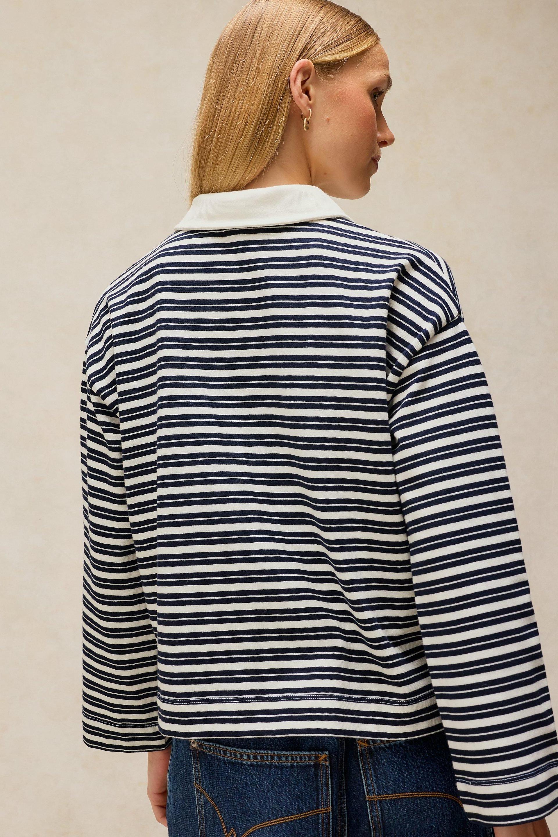 A woman from behind wearing a white and navy striped organic cotton rugby top.