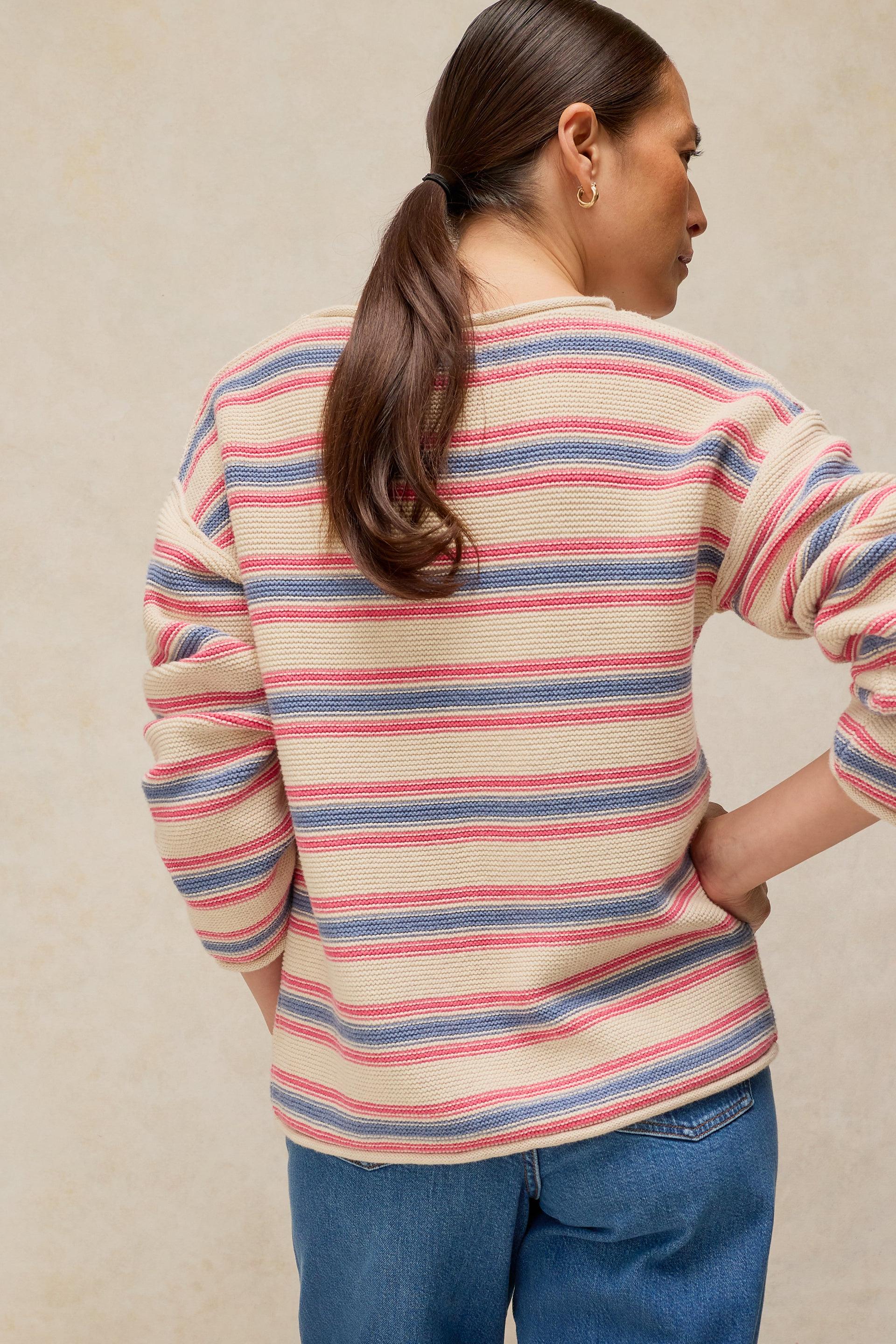 Woman seen from behind wearing a colorful striped sweater made of organic cotton