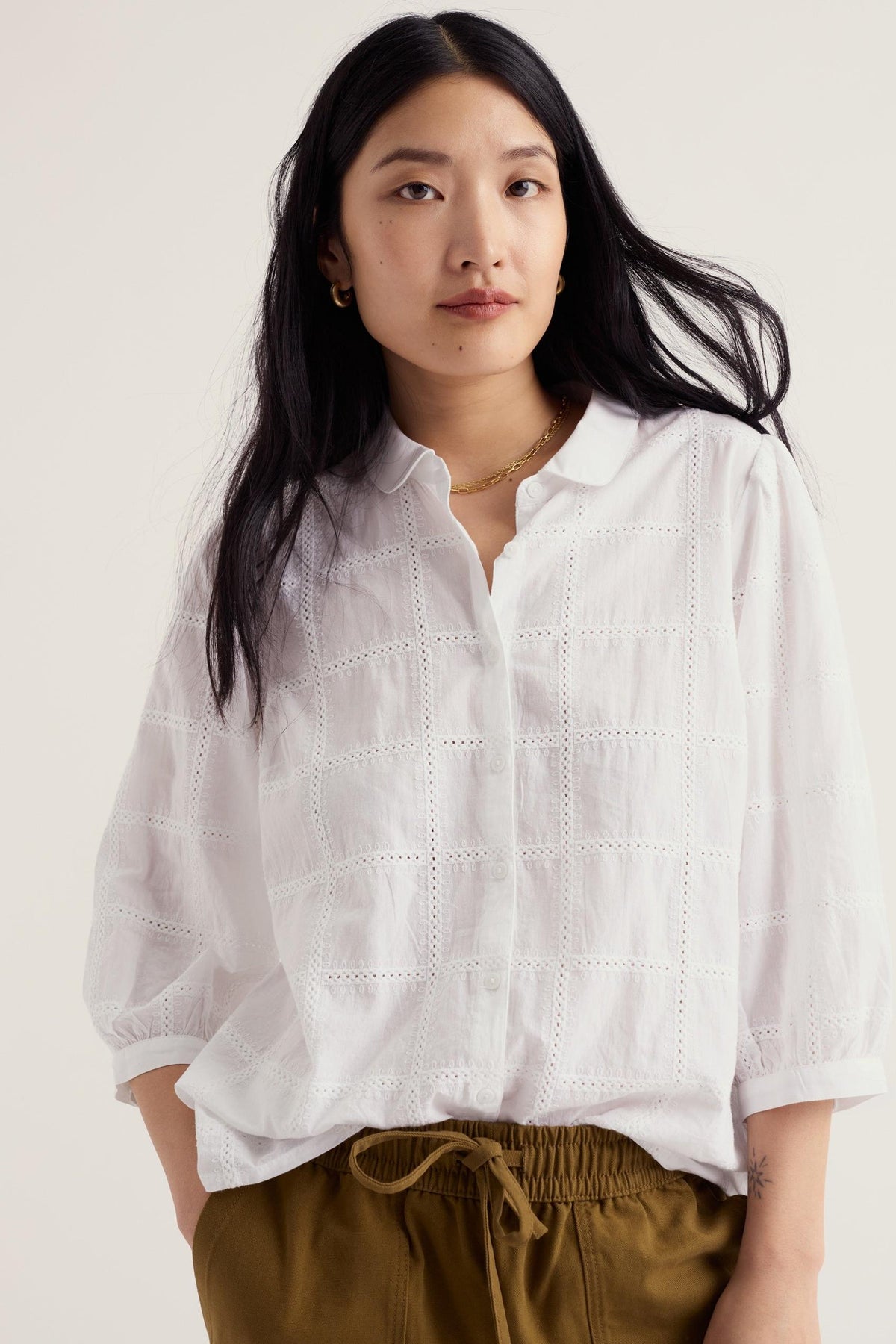 Woman posing in a white Seasalt Cornwall organic cotton blouse with delicate embroidery details.