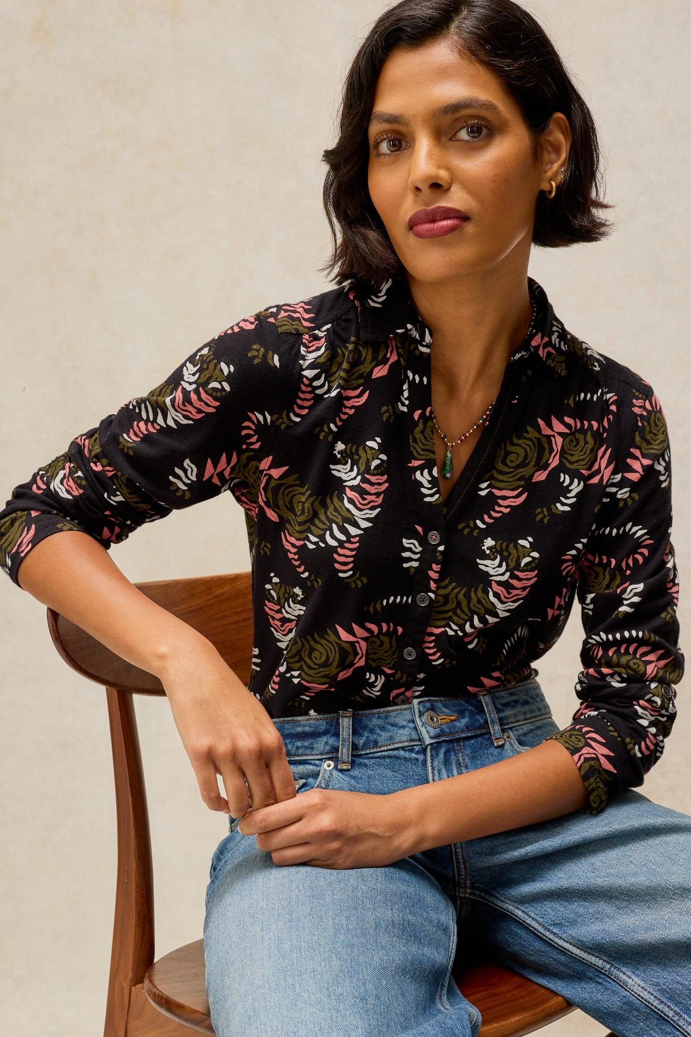 Woman posing in a black cotton jersey shirt with a colourful floral print from White Stuff.