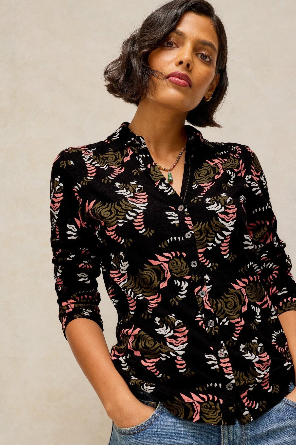 A woman wearing a black White Stuff cotton shirt with a patterned print and a collared neckline.