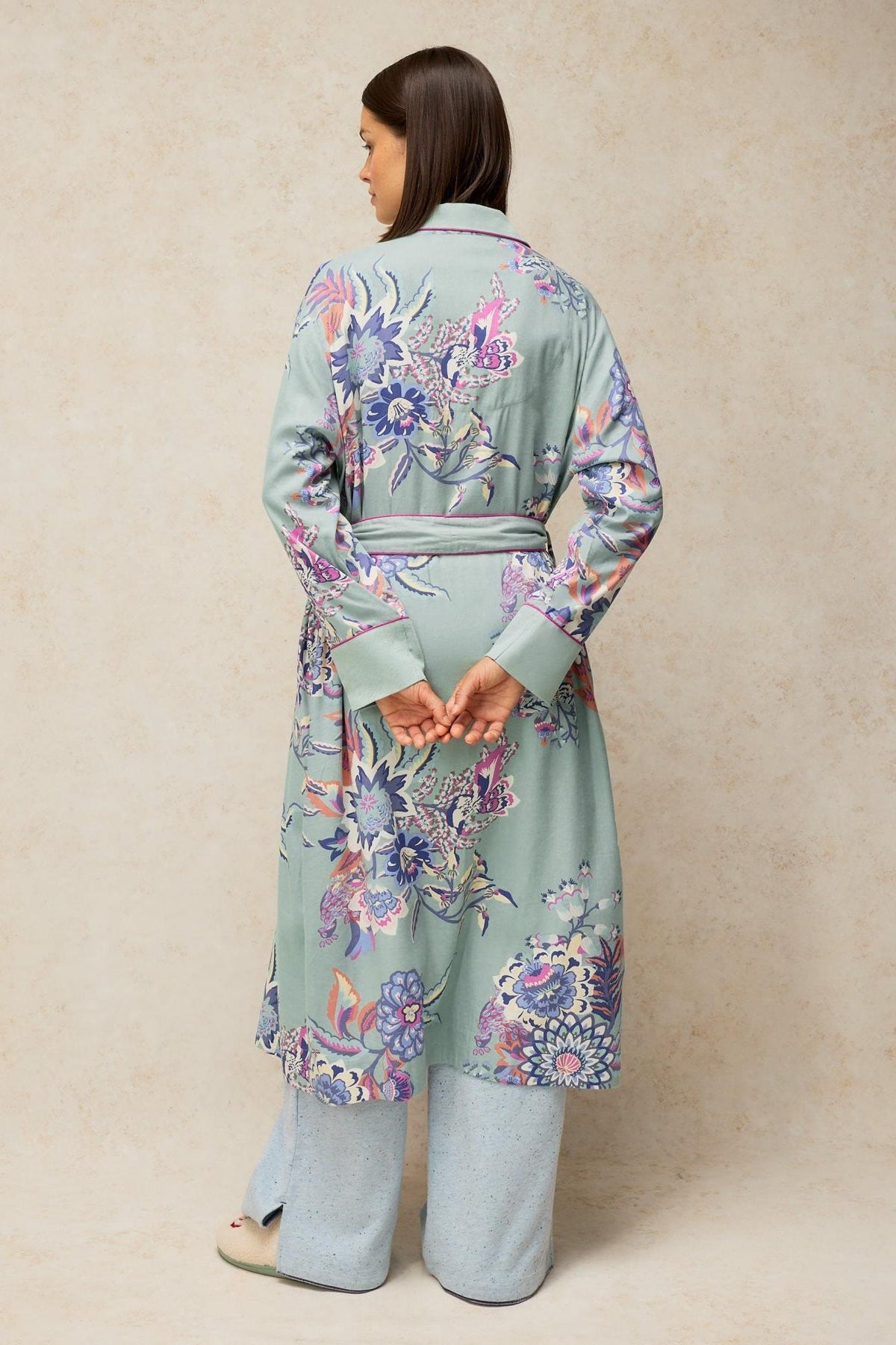 A woman seen from behind wearing a blue patterned White Stuff dressing gown over loungewear trousers.