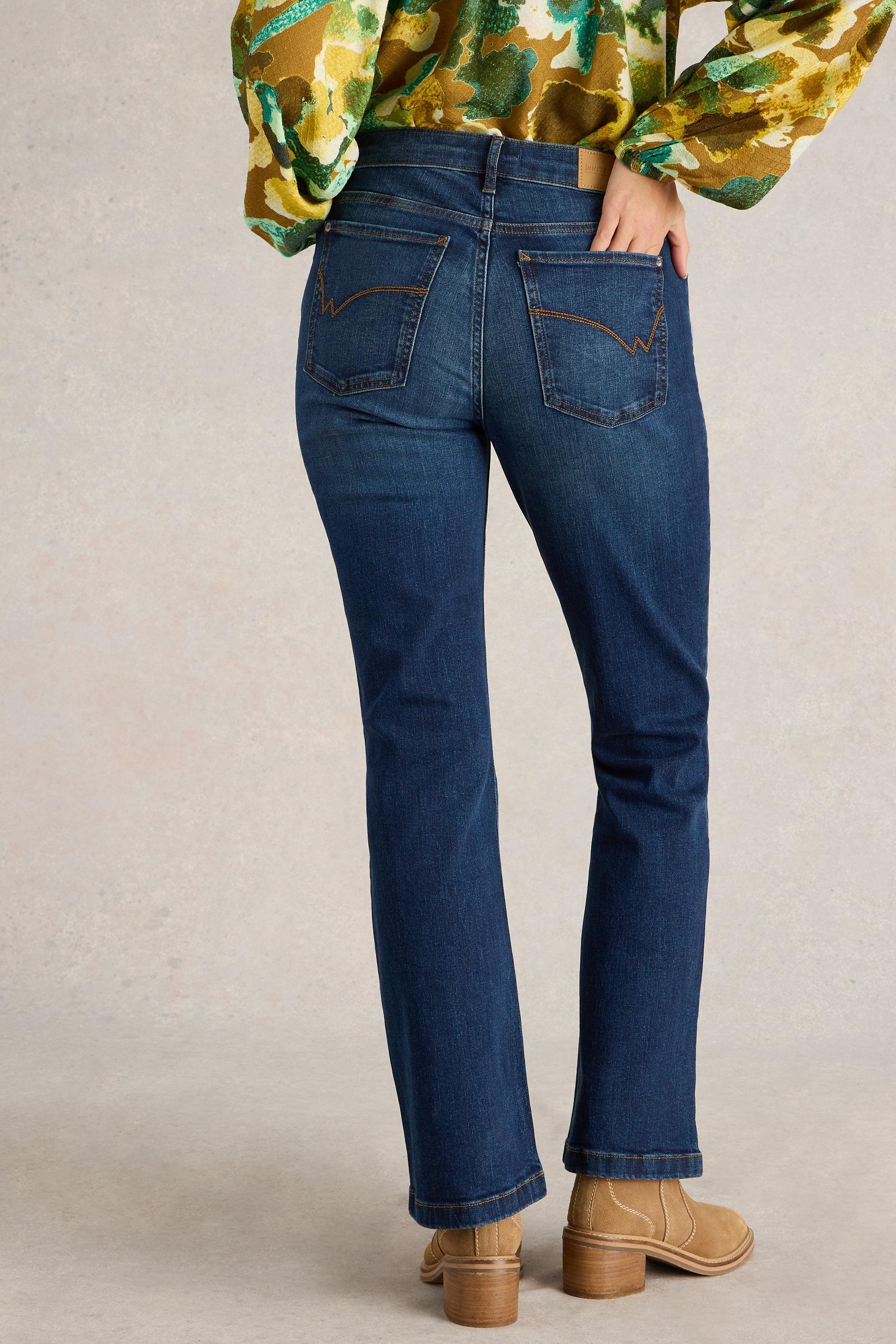 Rear view of a woman wearing blue White Stuff bootcut jeans and a patterned blouse.