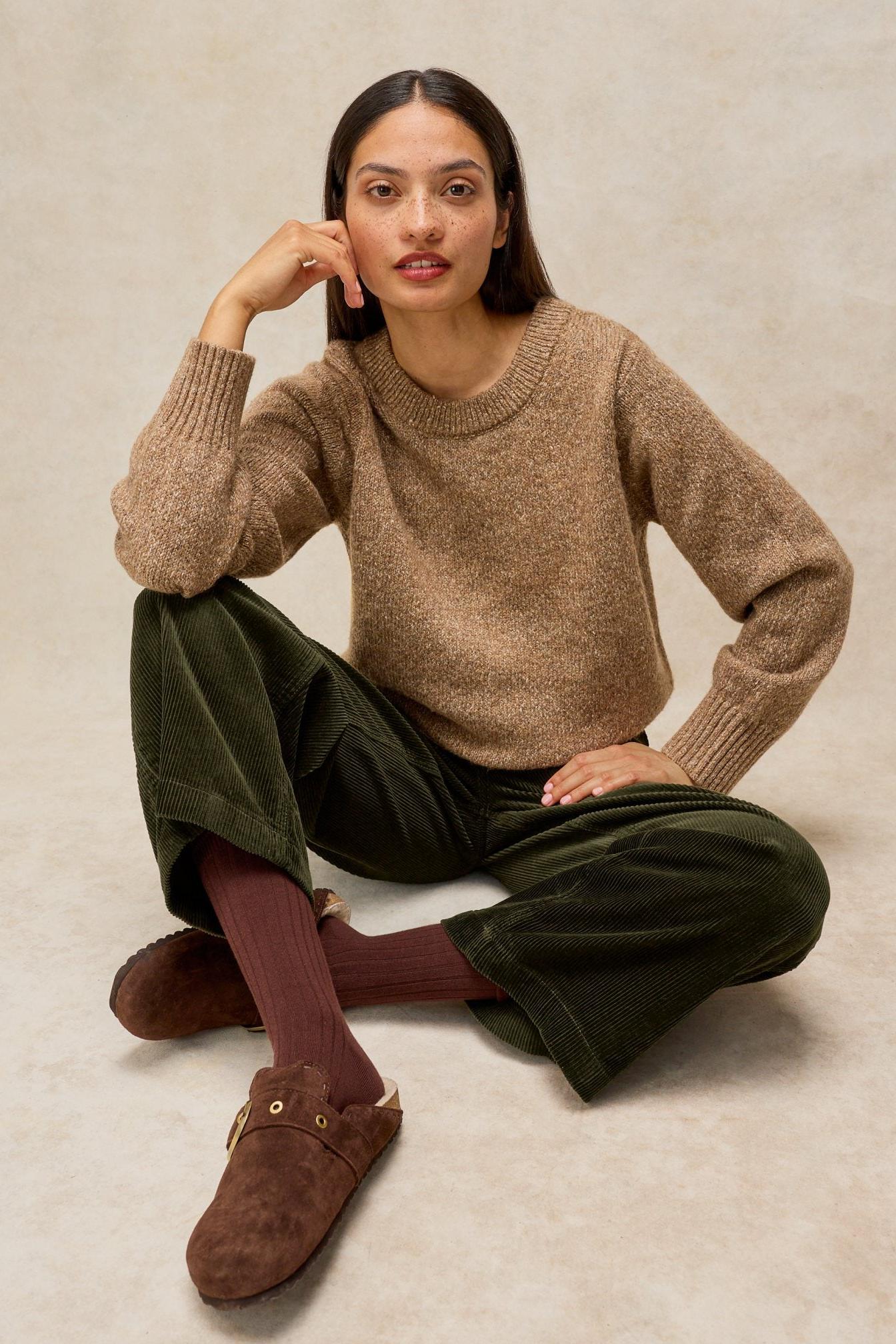 A woman wearing comfortable White Stuff cord trousers and a beige knit sweater.