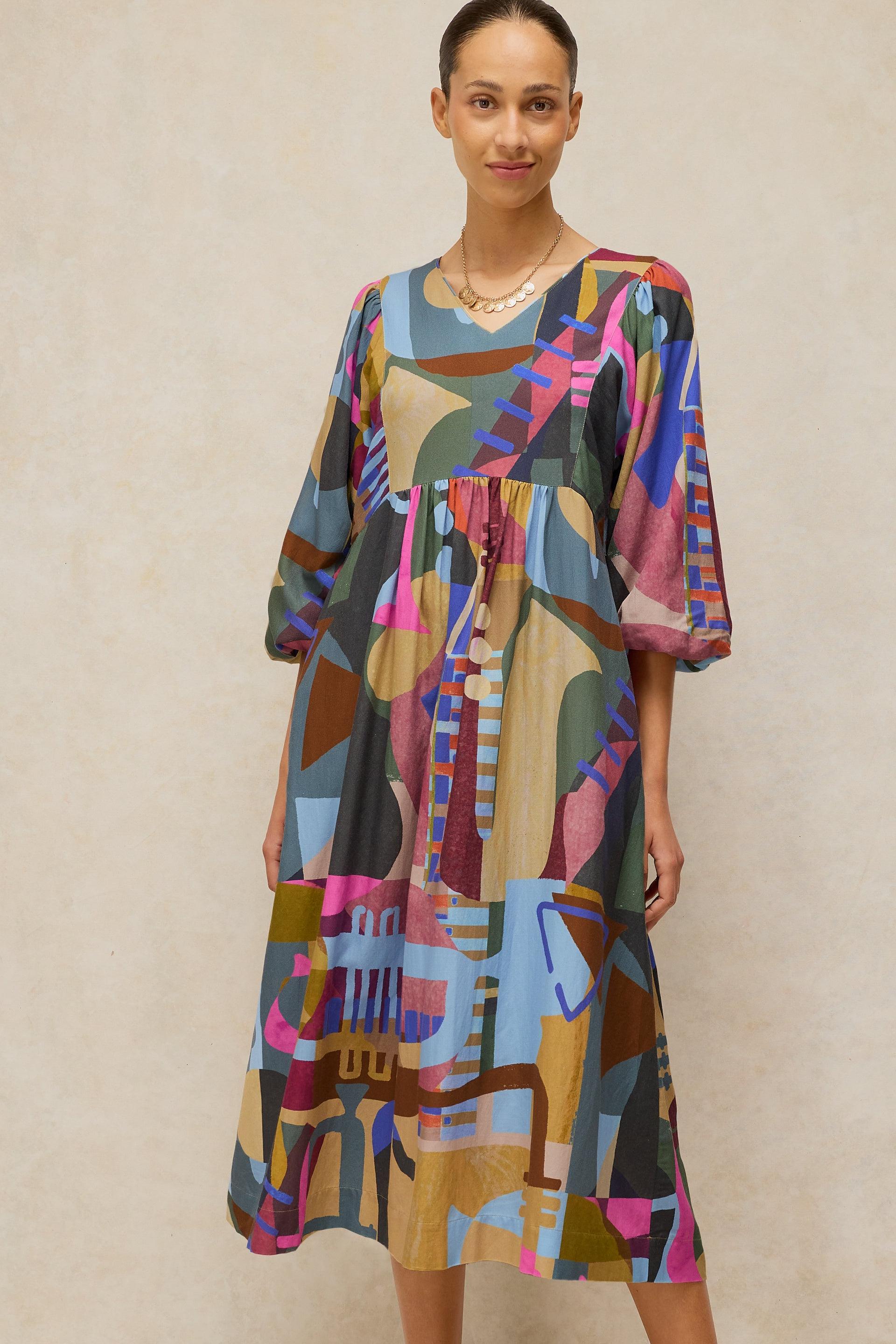 A woman wearing a vibrant abstract print midi dress made from sustainable Ecovero fabric.