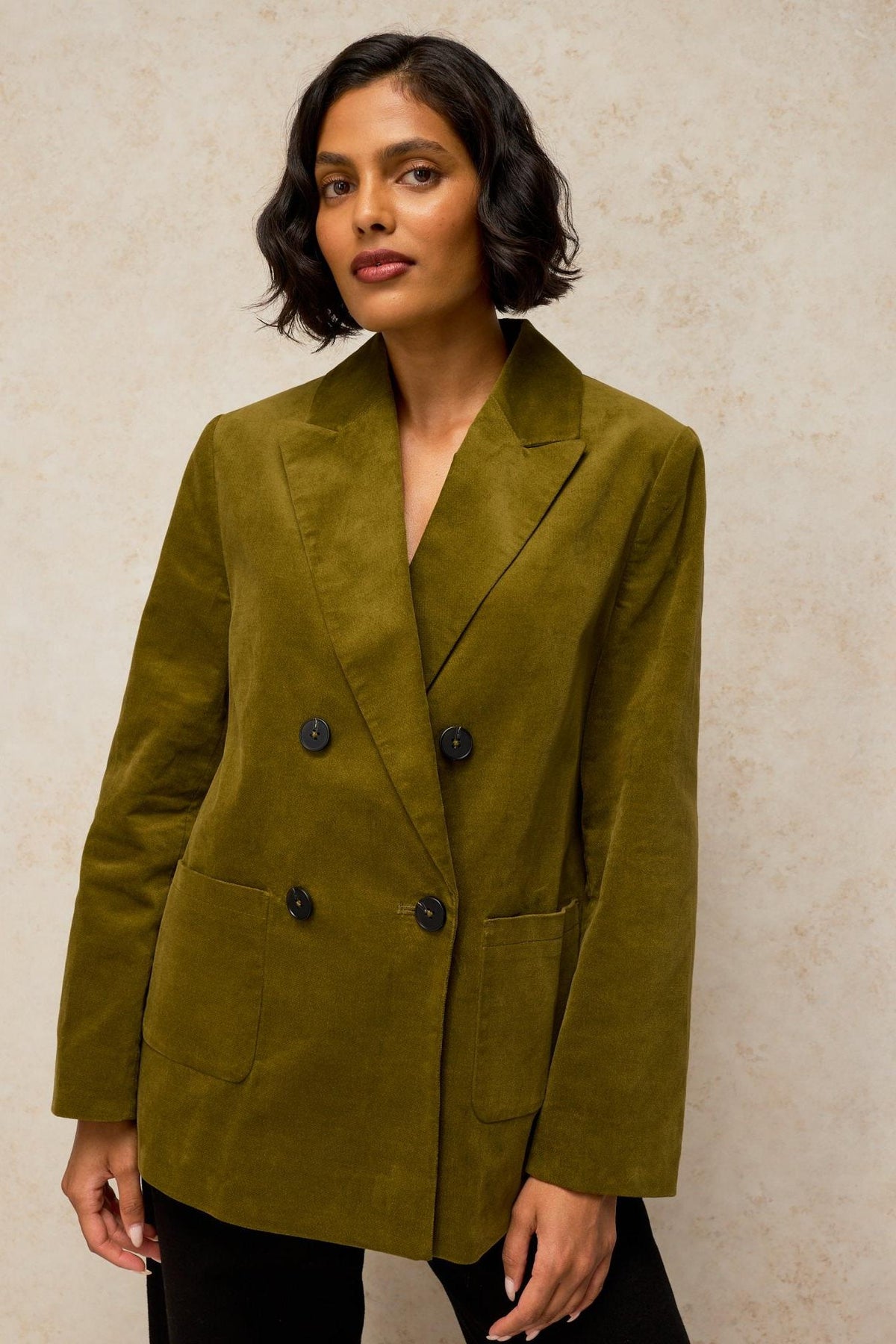 A woman wearing a stylish olive green velvet blazer for office or evening wear.