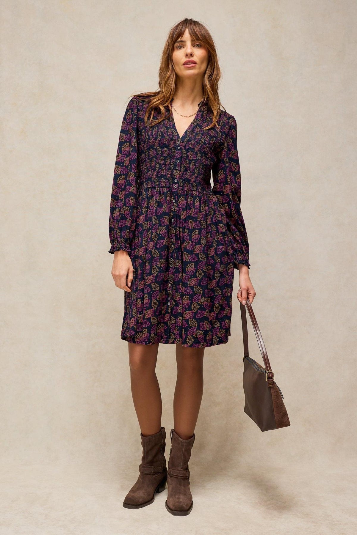 Woman standing in a knee-length White Stuff organic cotton dress with a dark floral print and brown ankle boots.
