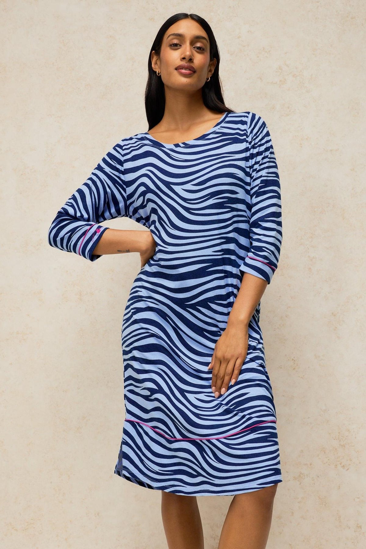 A woman modeling a blue zebra print organic cotton nightdress from White Stuff against a neutral studio background.