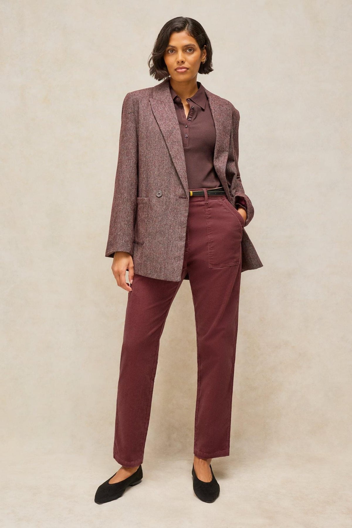 A woman wearing a brown blazer, polo shirt, and White Stuff organic cotton cord trousers.