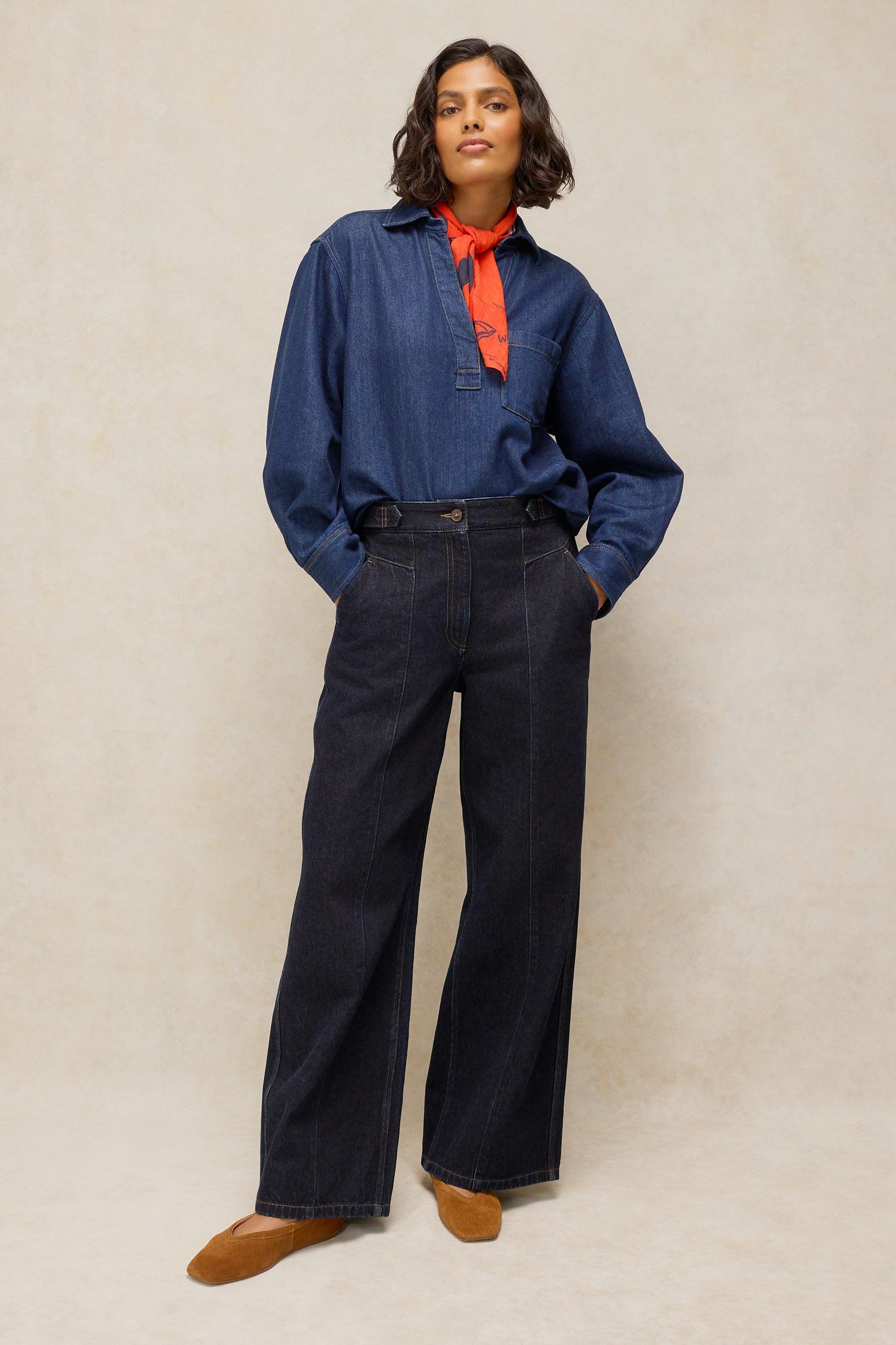 Woman wearing a stylish White Stuff dark denim shirt and wide-leg trousers made of organic cotton.