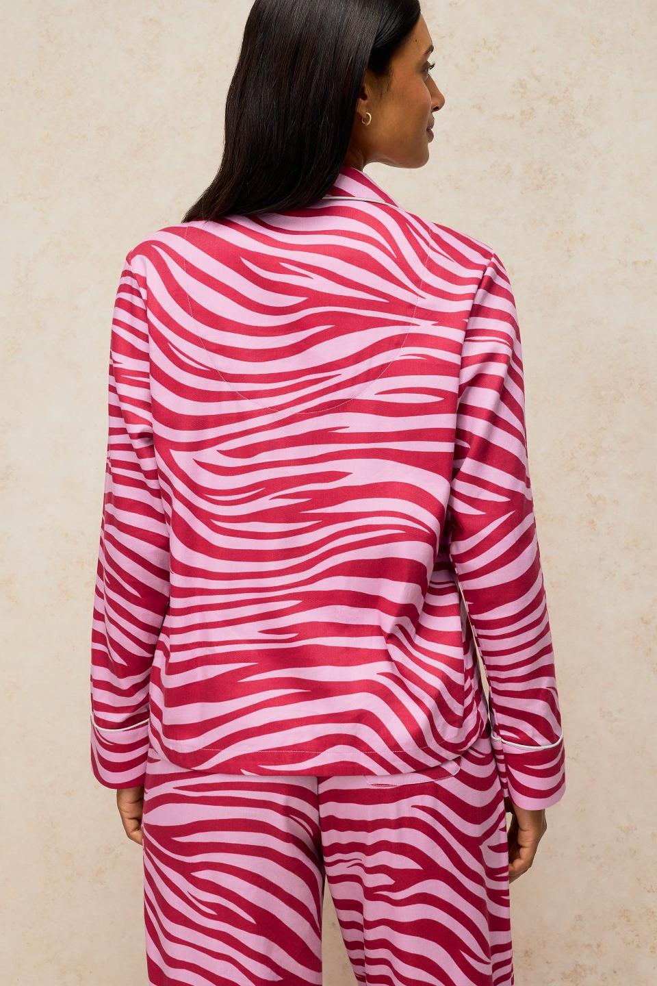 A woman seen from behind wearing a pink and dark pink zebra print White Stuff organic cotton pyjama top.
