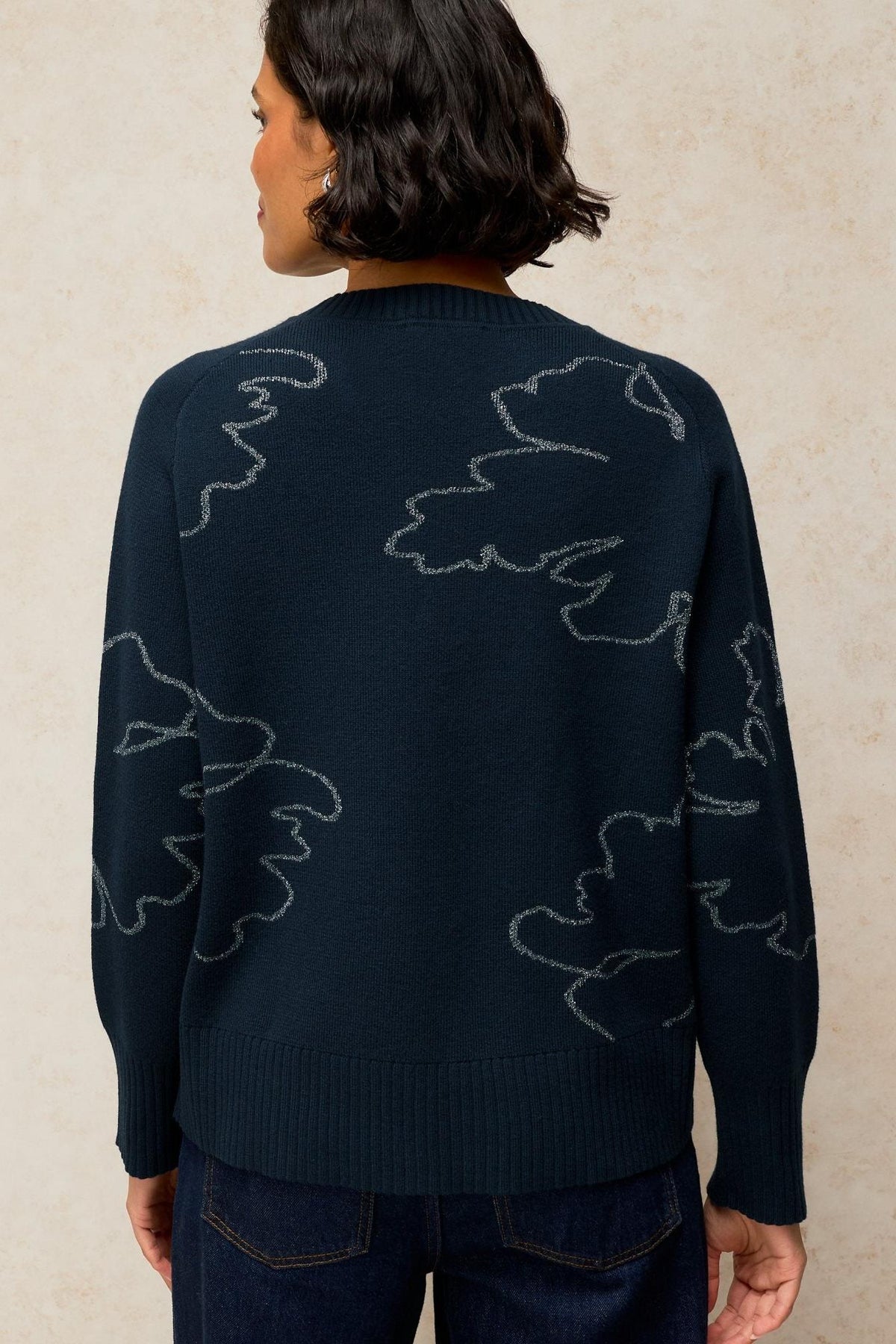 Rear view of a woman wearing a black jumper with subtle silver sparkle line art details.