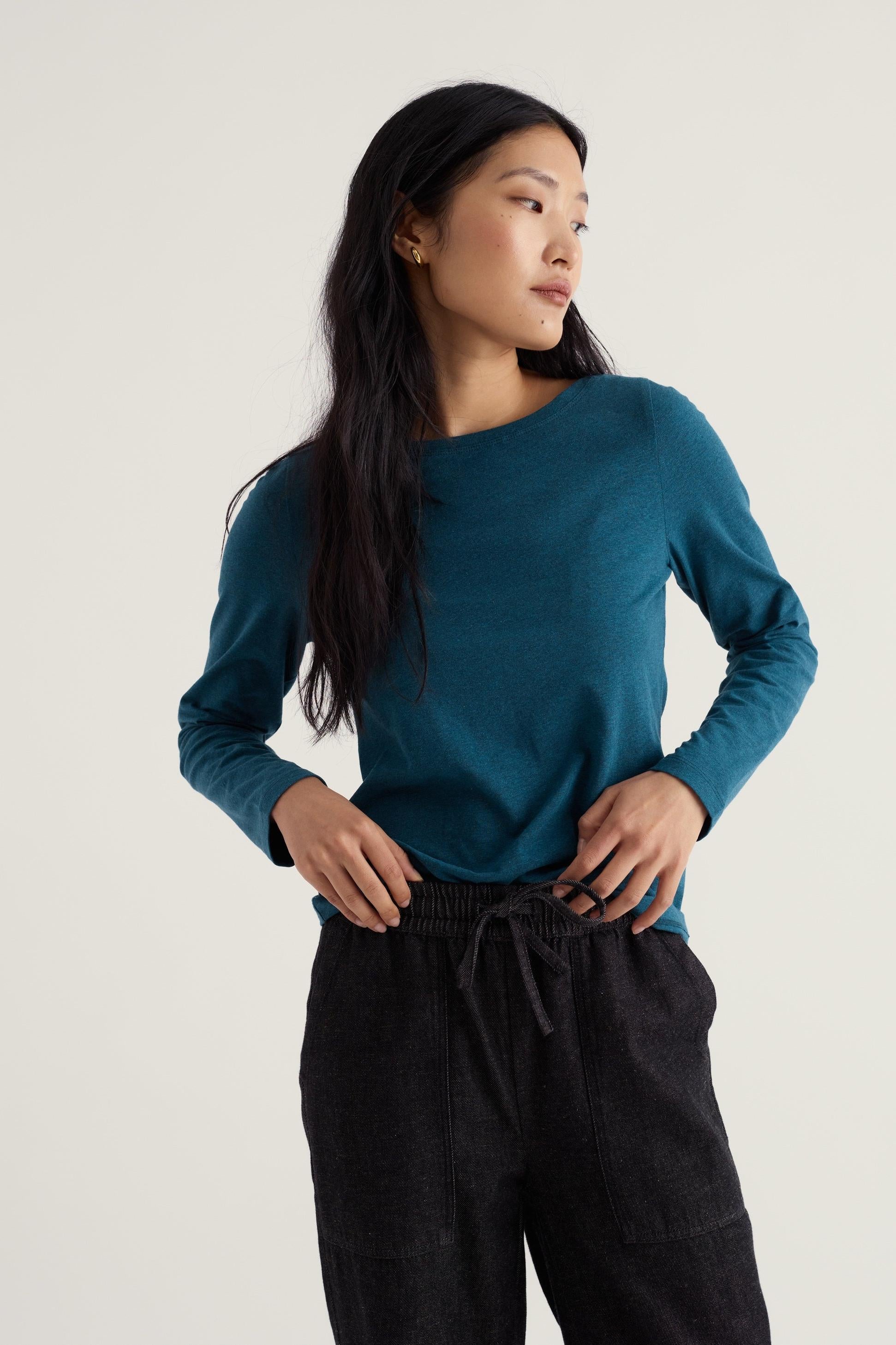 A woman wearing a Seasalt Cornwall long sleeve organic cotton top in a deep blue shade.