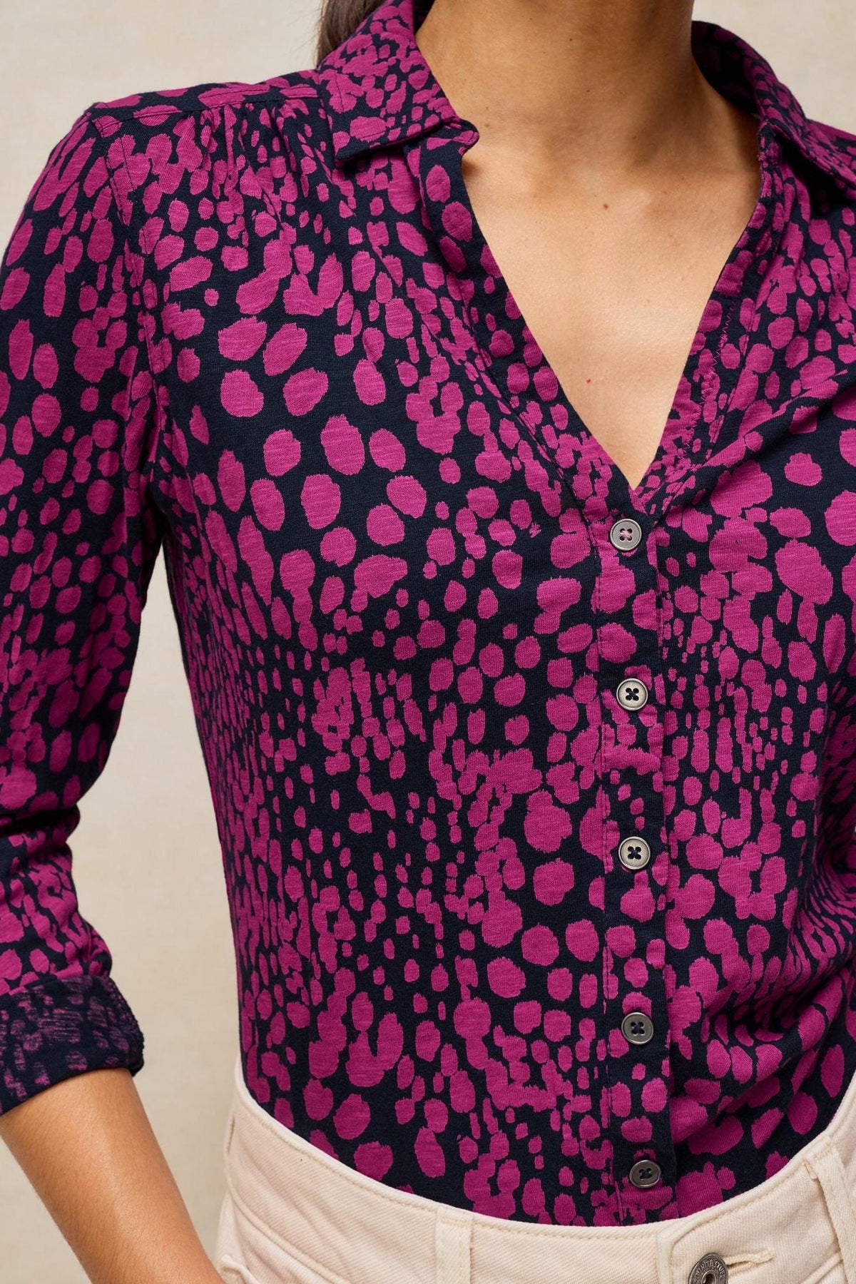 A woman wearing a casual long-sleeve Annie jersey blouse with a pink and dark navy dot print.