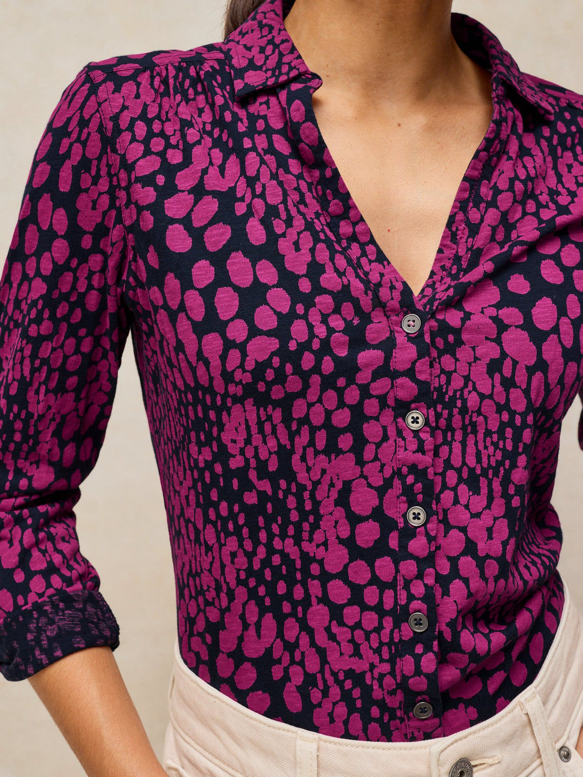 A woman wearing a casual long-sleeve Annie jersey blouse with a pink and dark navy dot print.