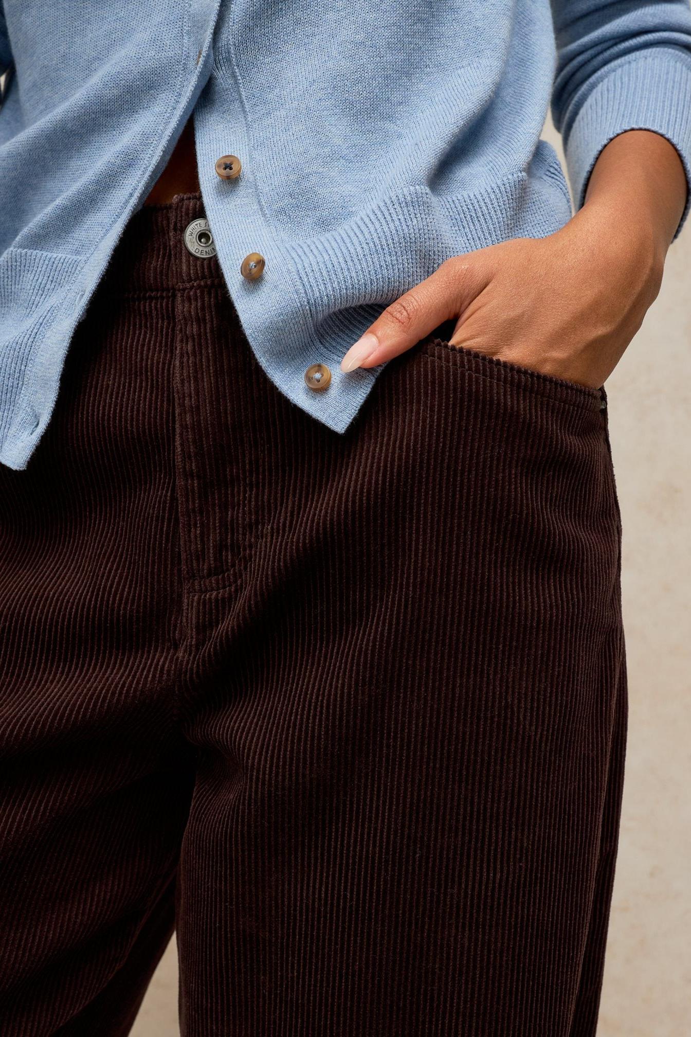 Close up of woman wearing brown cord trousers from White Stuff with a light blue cardigan.