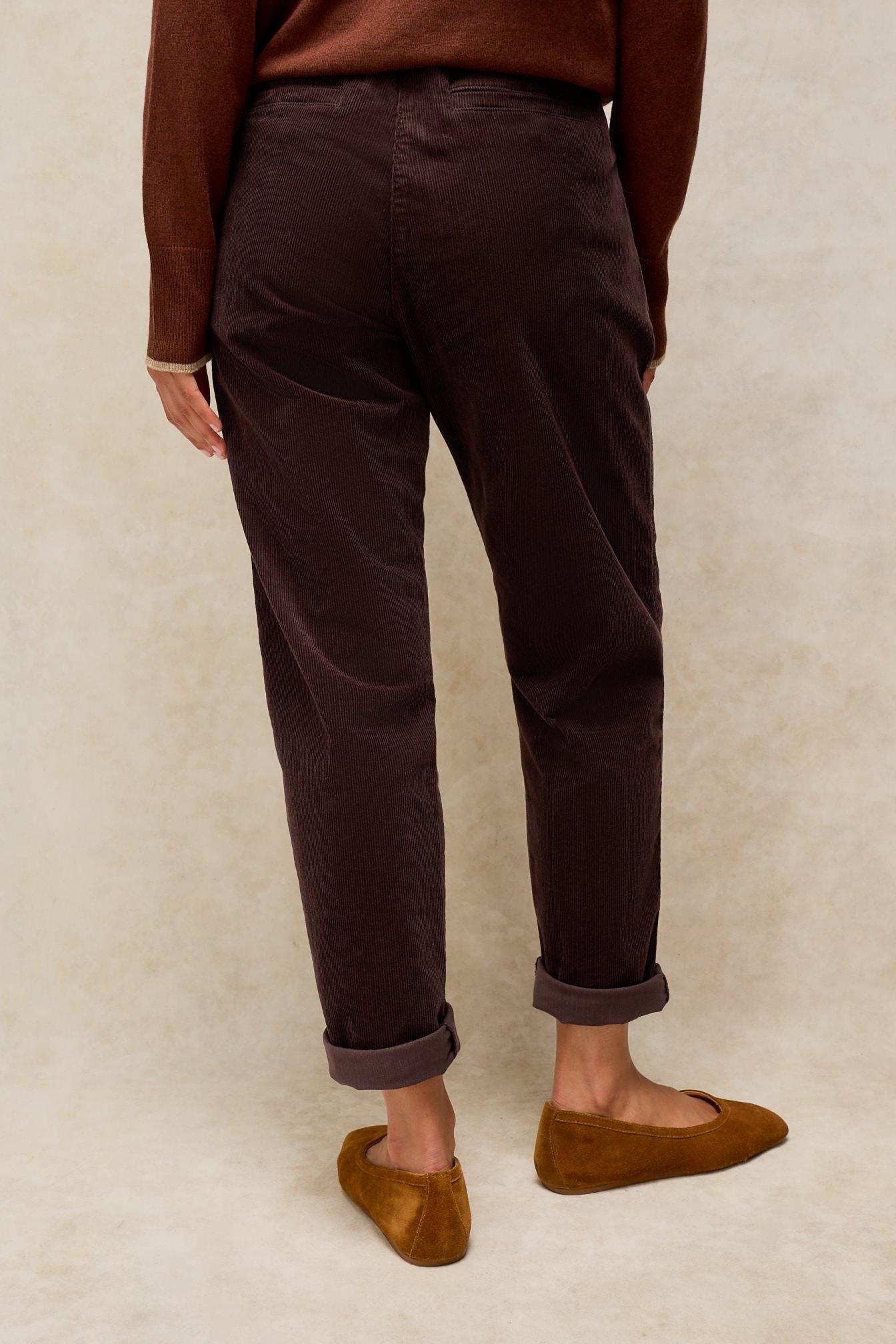 A person wearing brown organic cotton corduroy trousers paired with a brown sweater and suede flats.