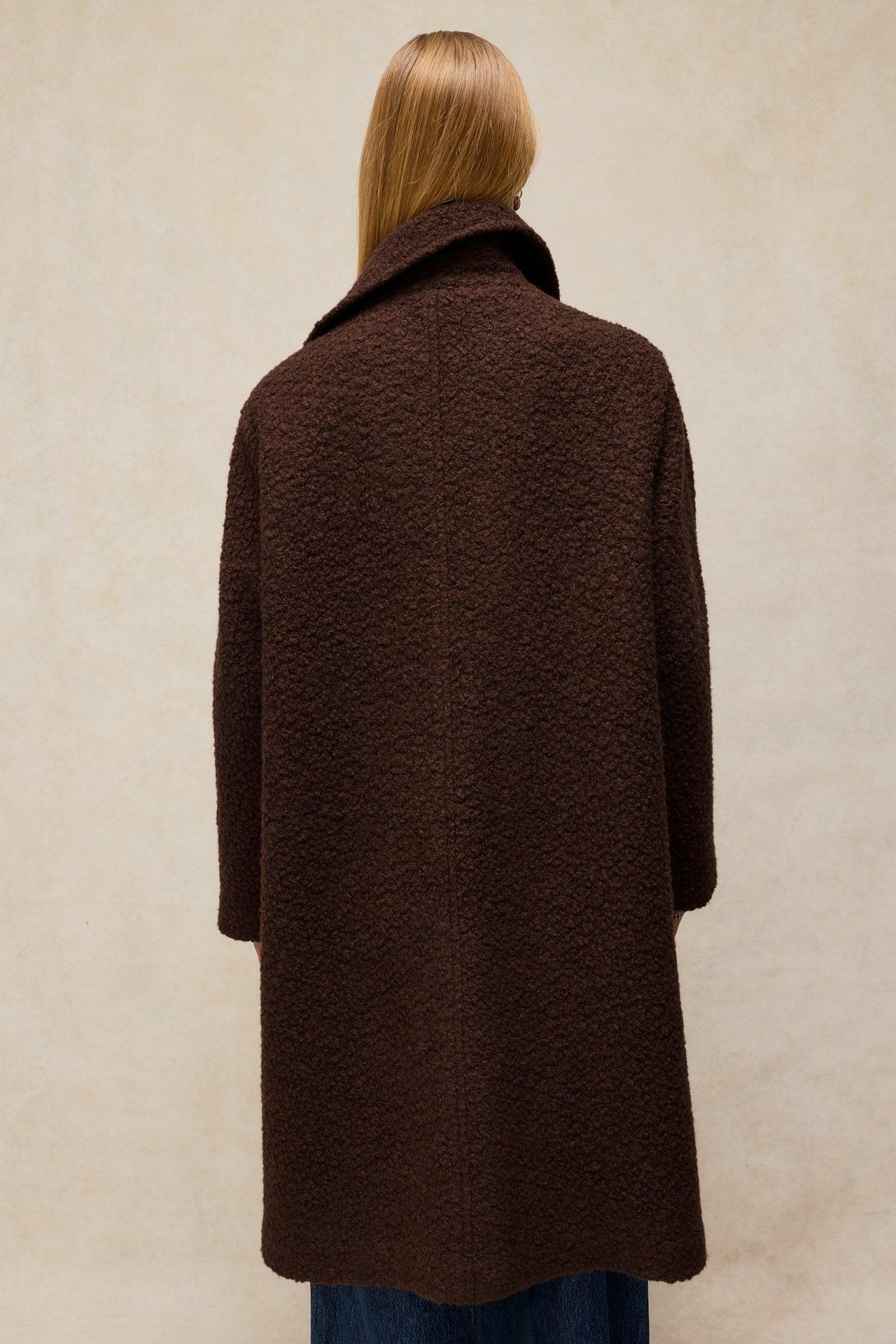 A woman seen from behind wearing a brown textured wool winter coat by White Stuff.