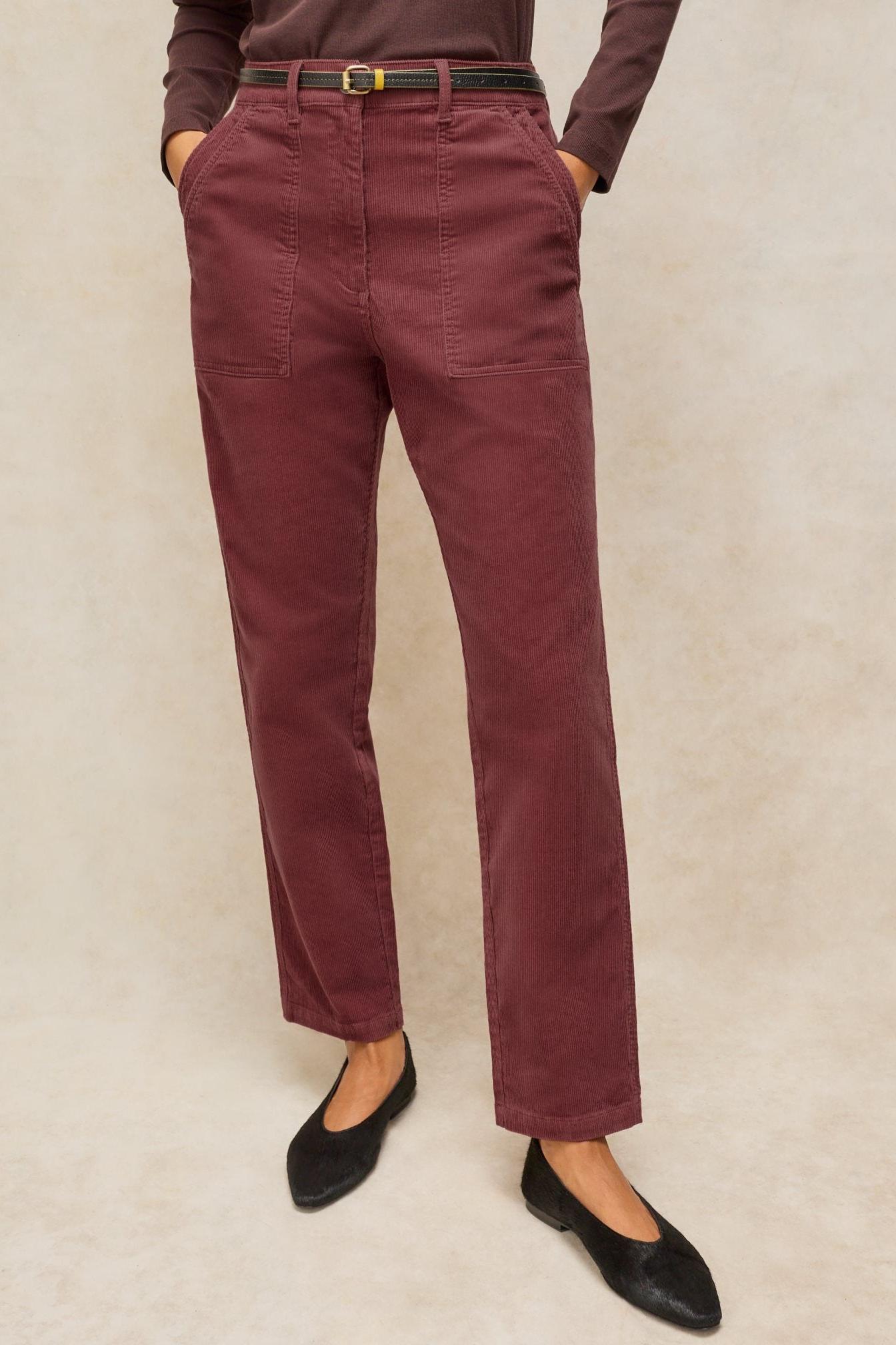 Model wearing dark burgundy organic cotton cord trousers and black flats against a neutral background.