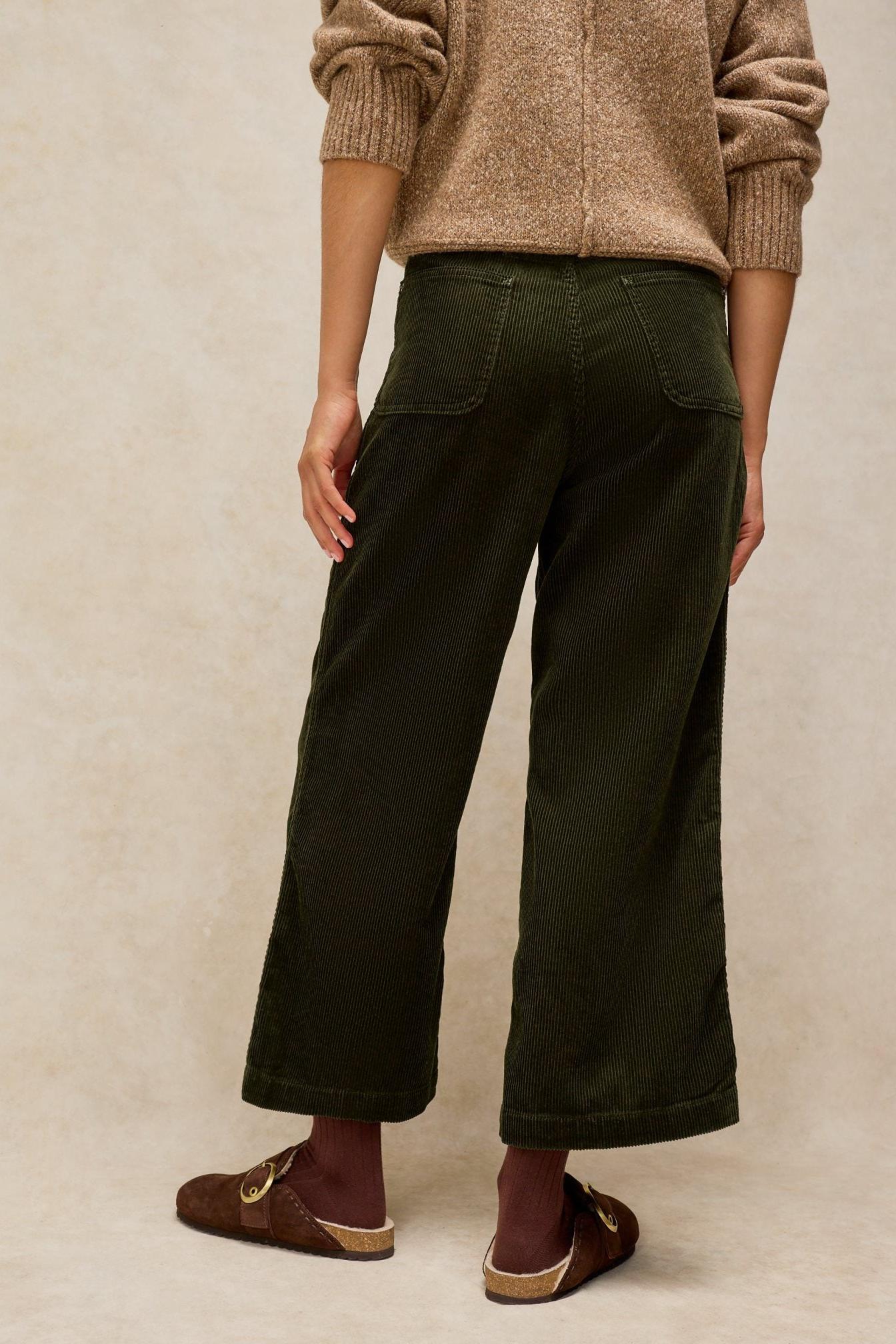 Woman standing from behind wearing dark green White Stuff cord trousers and a beige knit sweater.