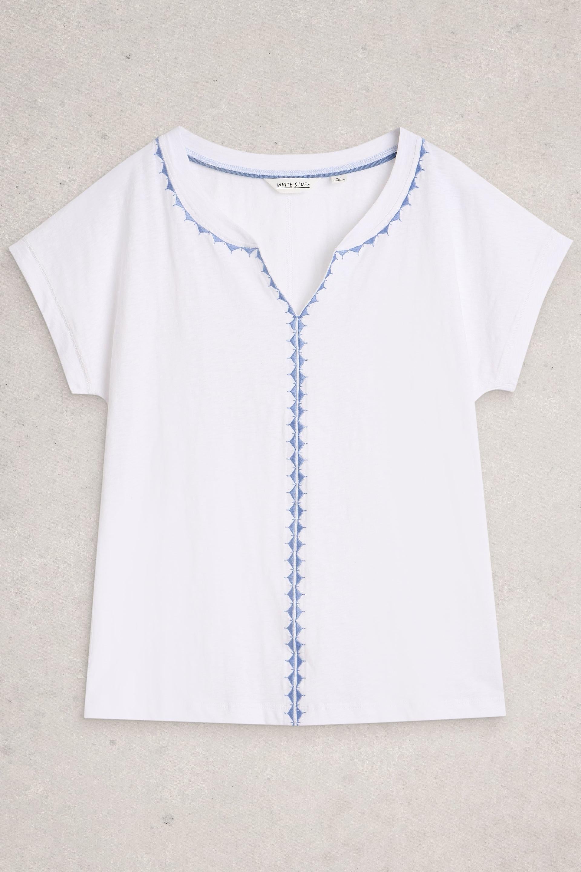 White Stuff top with blue stitching on a beige background