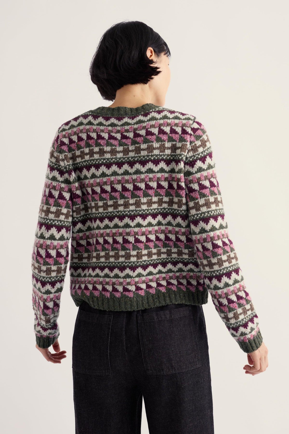 A woman wearing a Seasalt Cornwall fairisle pattern merino wool and recycled nylon cardigan against a light background.