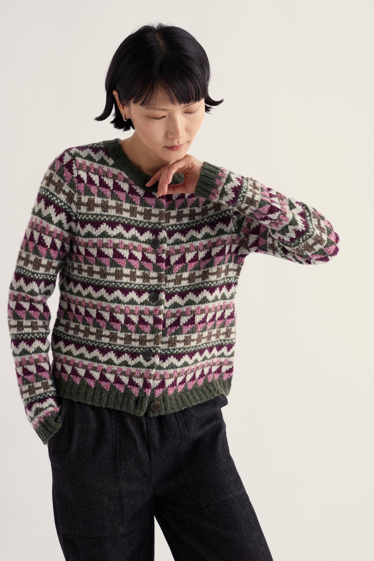 A woman wearing a Seasalt Cornwall fairisle pattern merino wool and recycled nylon cardigan against a light background.