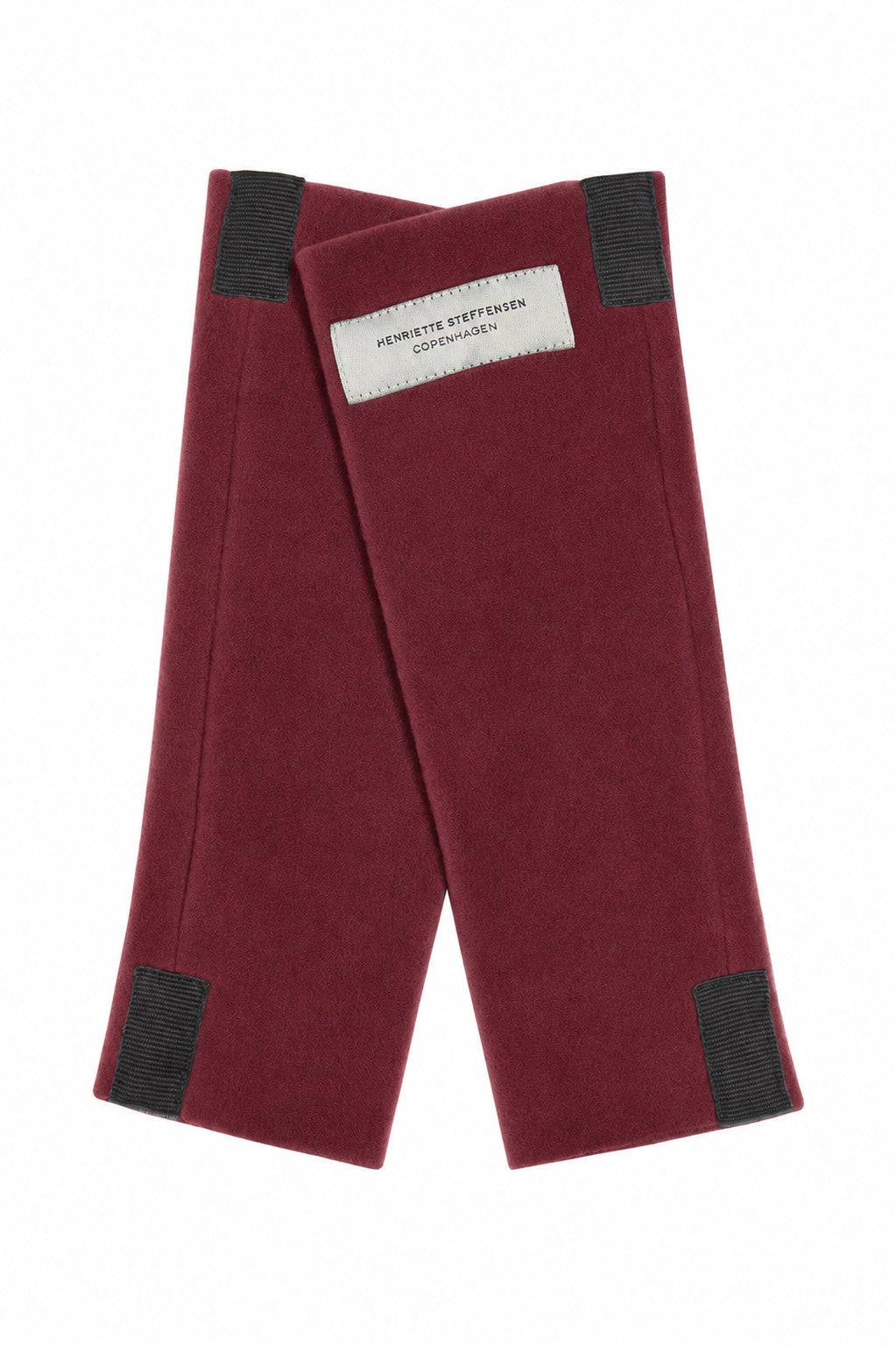 A pair of burgundy fleece wrist warmers with black detail and a white brand label 