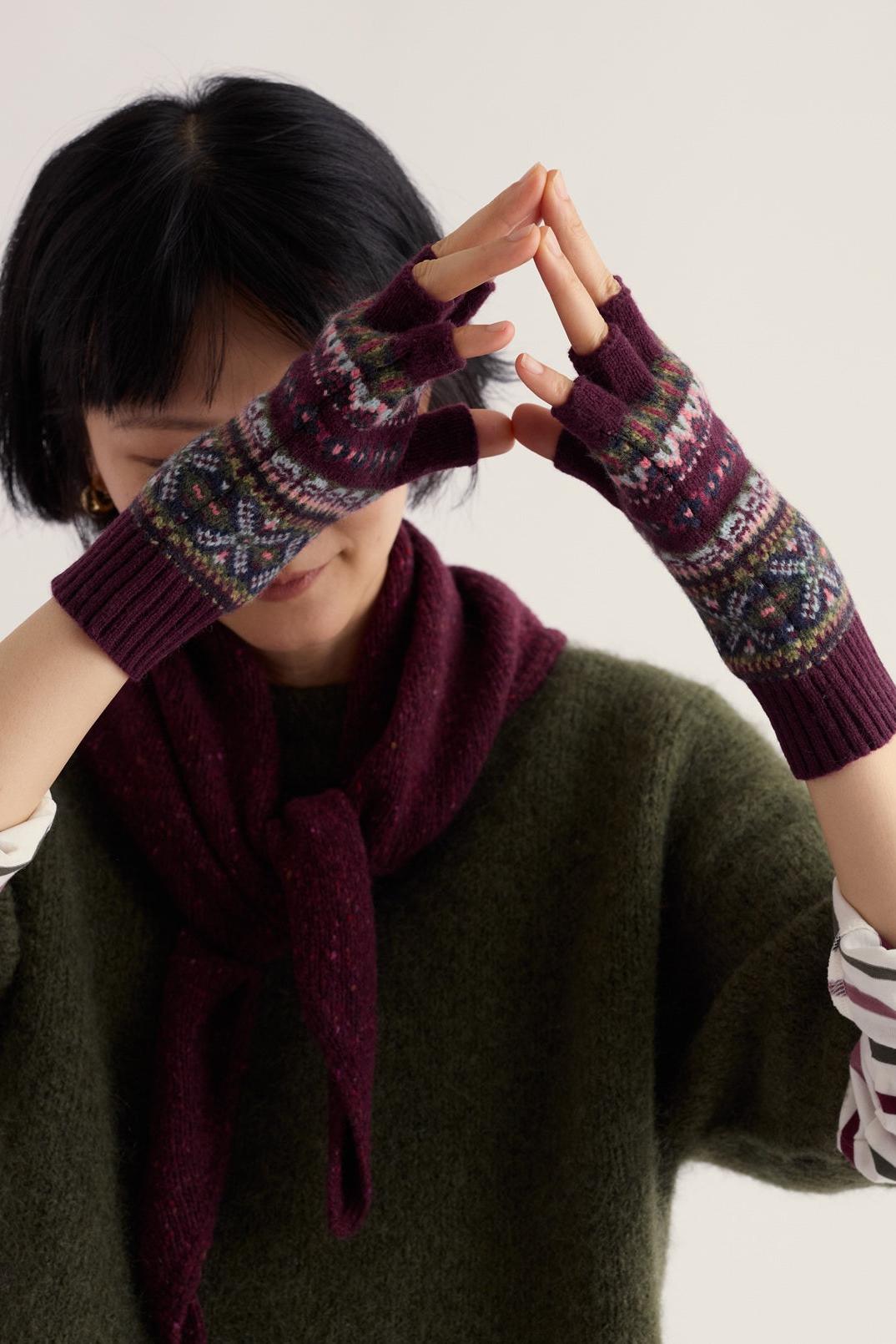 Woman wearing patterned wool knit fingerless gloves and a burgundy scarf.