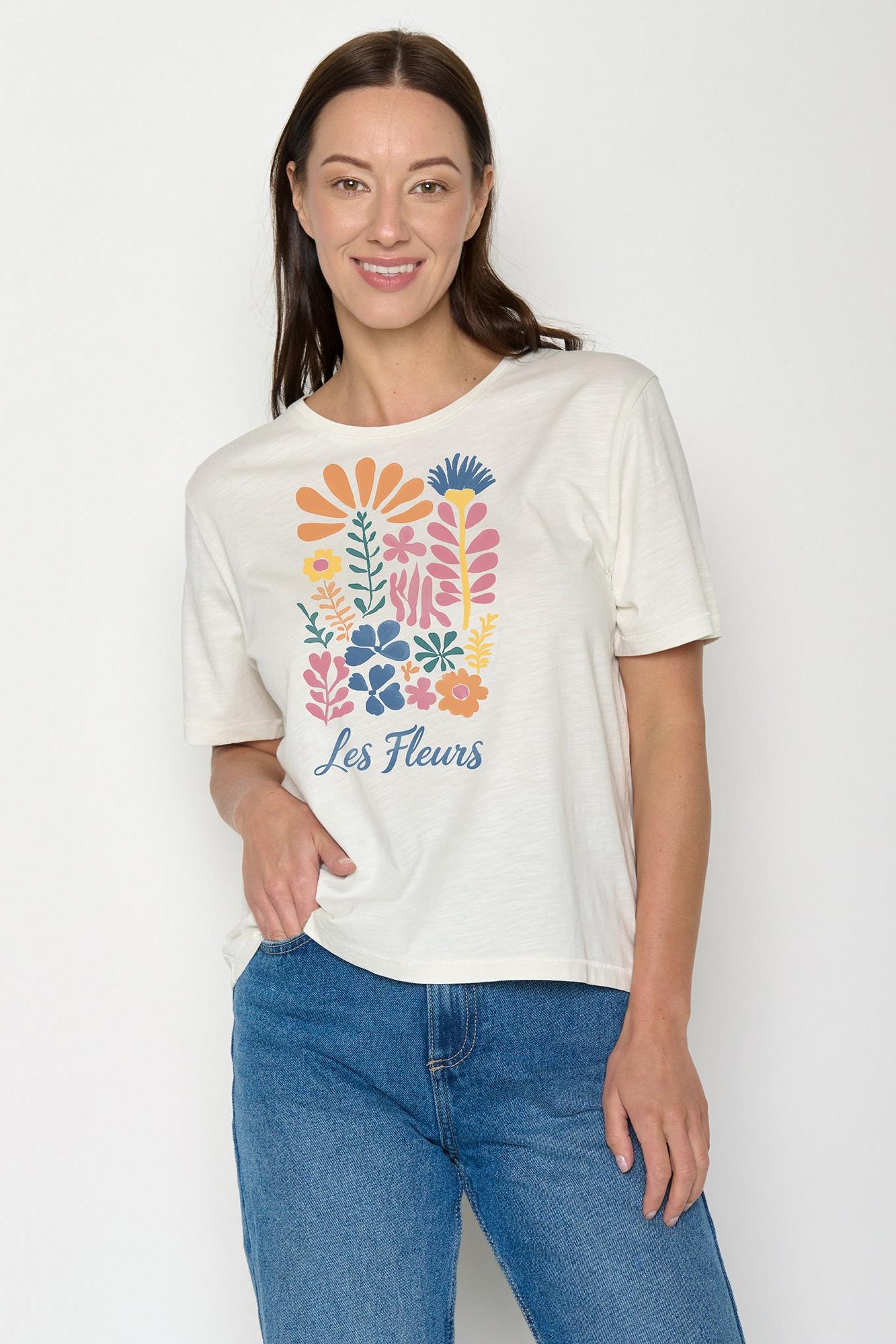 Woman wearing a white t-shirt with colorful floral design and 'Les Fleurs' text on a plain background