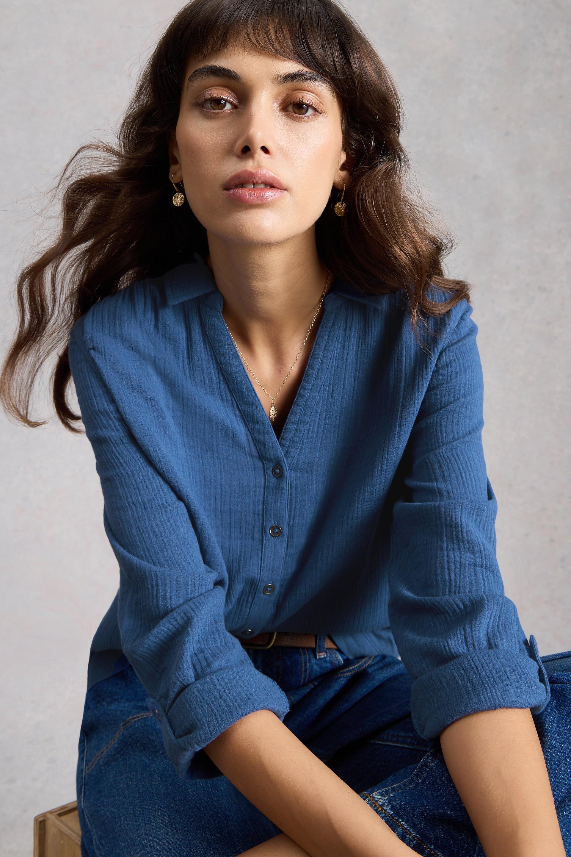 Woman wearing a blue textured shirt against a neutral background