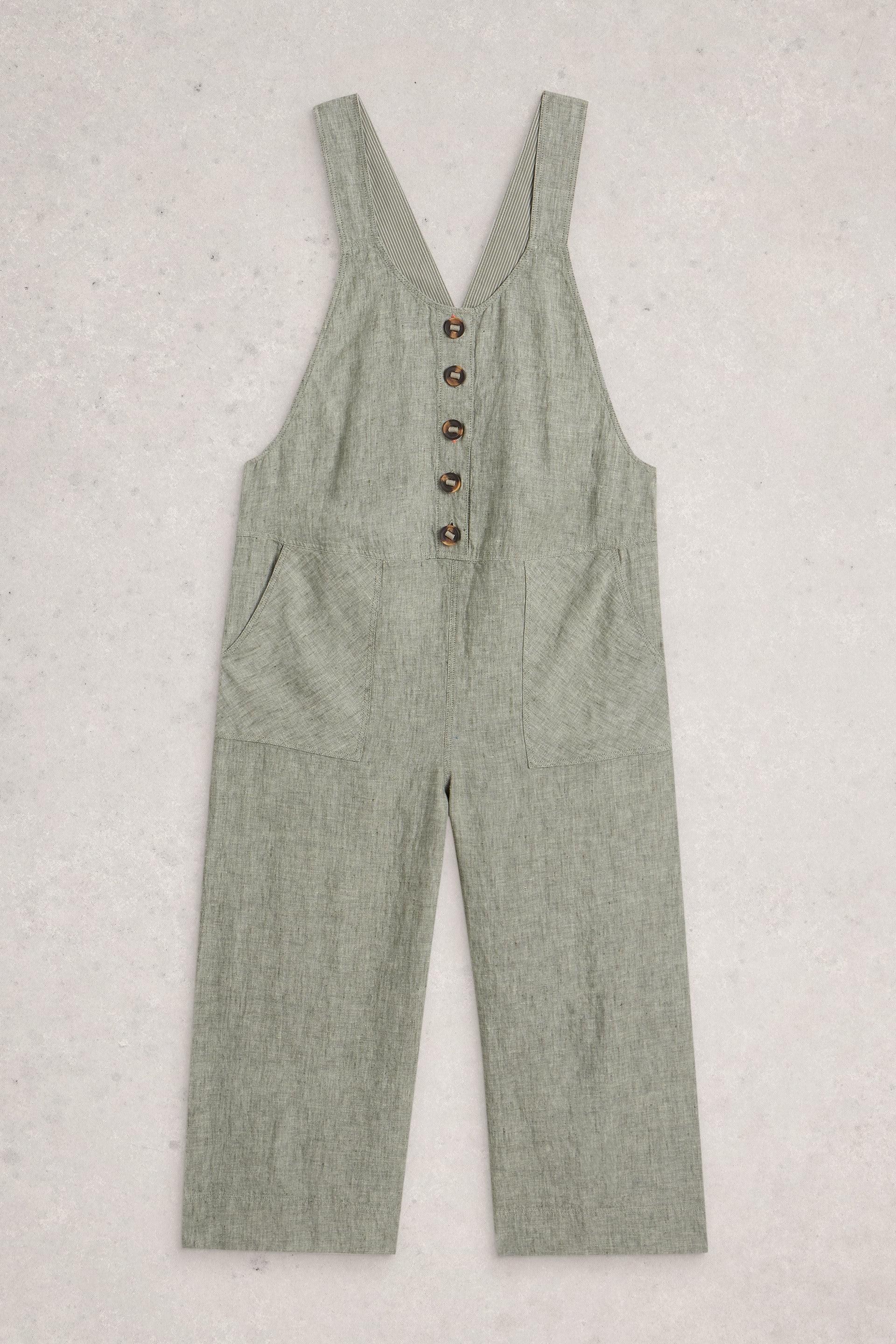 Green linen dungarees with button details on a light gray background
