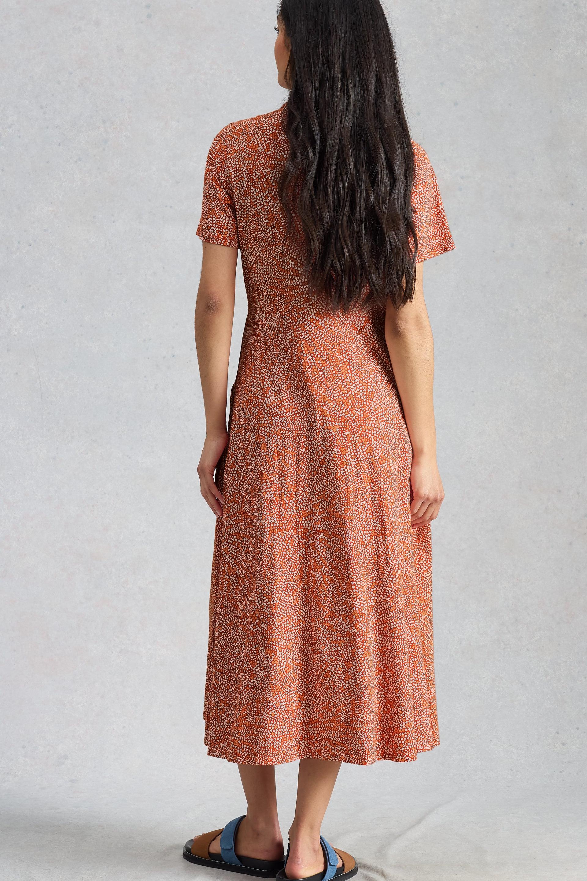 Woman wearing a patterned organic cotton and linen dress against a plain background